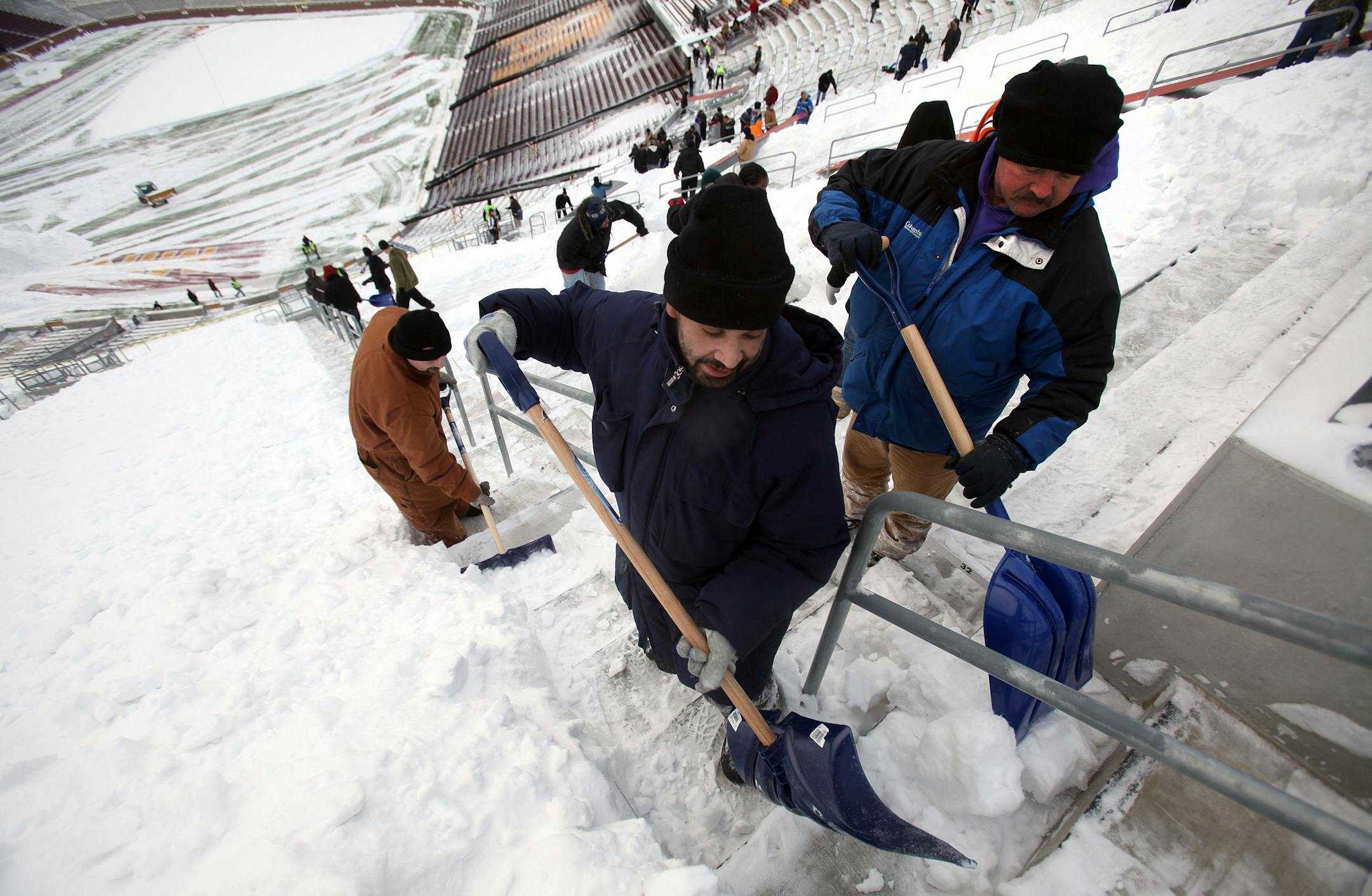 Marcos Enriquez, of St. Paul, left, and Roger Armbrust, of Rochester, shoveled snow into piles for removal from the upper deck seating at TCF Stadium. This was the first time in the stadium for both men.