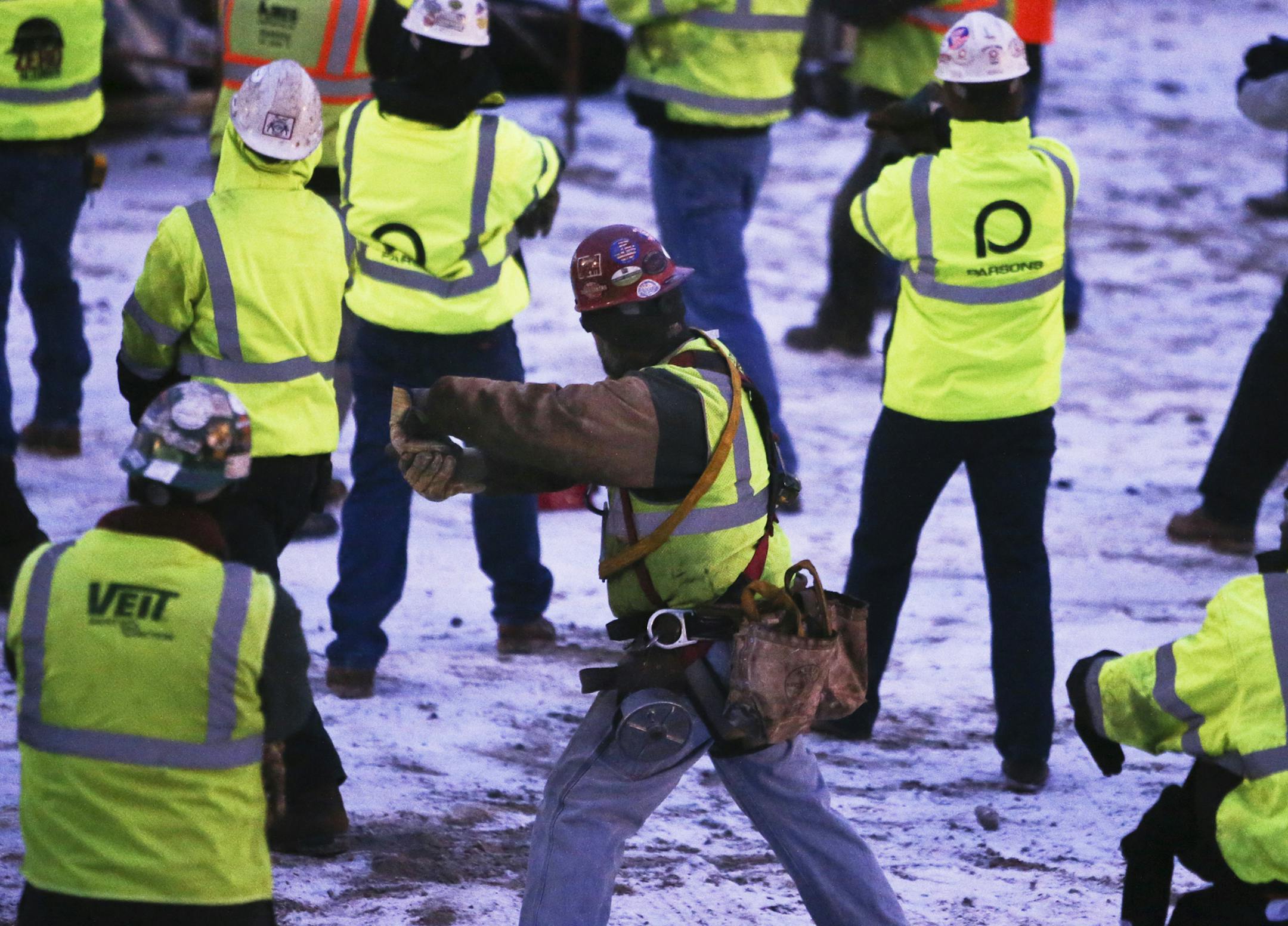 Mortenson Construction workers and sub contract workers stretch before beginning their work day.
