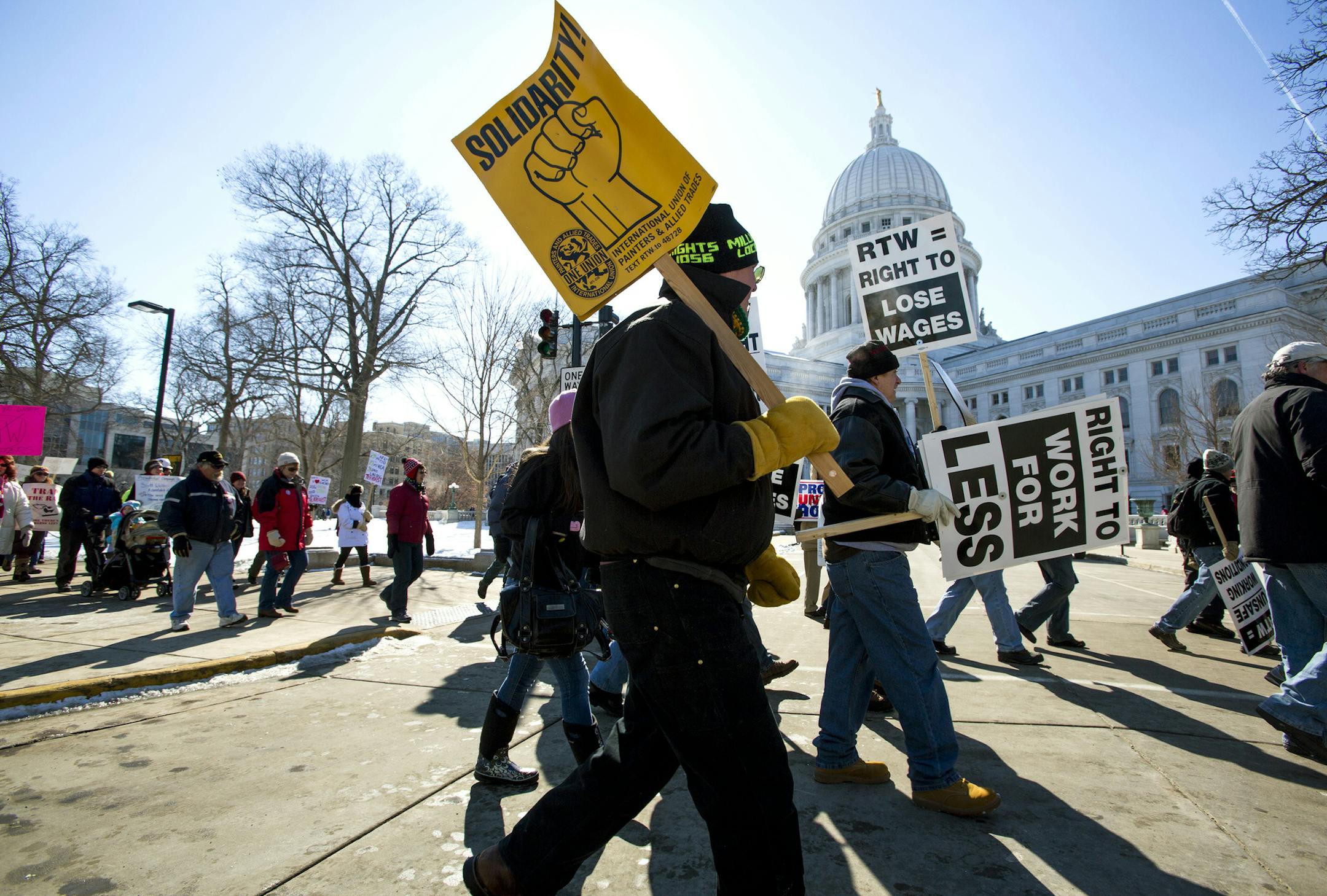 Protesters march around the Capitol after participating in a rally against a "right-to-work" proposal, on Saturday, Feb. 28, 2015, in Madison, Wis. Thousands of Wisconsin union workers rallied at the Capitol Saturday to protest a "right-to-work" proposal that would outlaw the mandatory payment of union dues, but the crowd was much smaller than those in 2011 against Gov. Scott Walker's law stripping public sector unions of much of their power. (AP Photo/Wisconsin State Journal, Steve Apps)