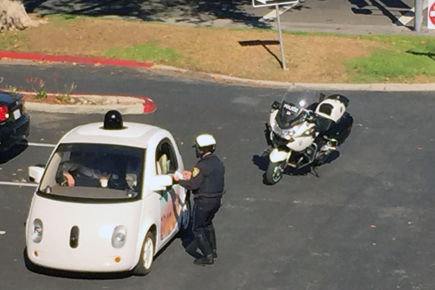 In this Thursday, Nov. 12, 2015 photo provided by Zandr Milewski, a California police officer pulls over a self-driving car specially designed by Google that was being tested on a local road in Mountain View, Calif. The police officer saw the car going a road-clogging 24 mph in a 35 mph zone and realized it was a Google Autonomous Vehicle. After getting closer to it he noticed that there was no one actually driving the car. The officer stopped the car and contacted the person&#x2020;behind the w