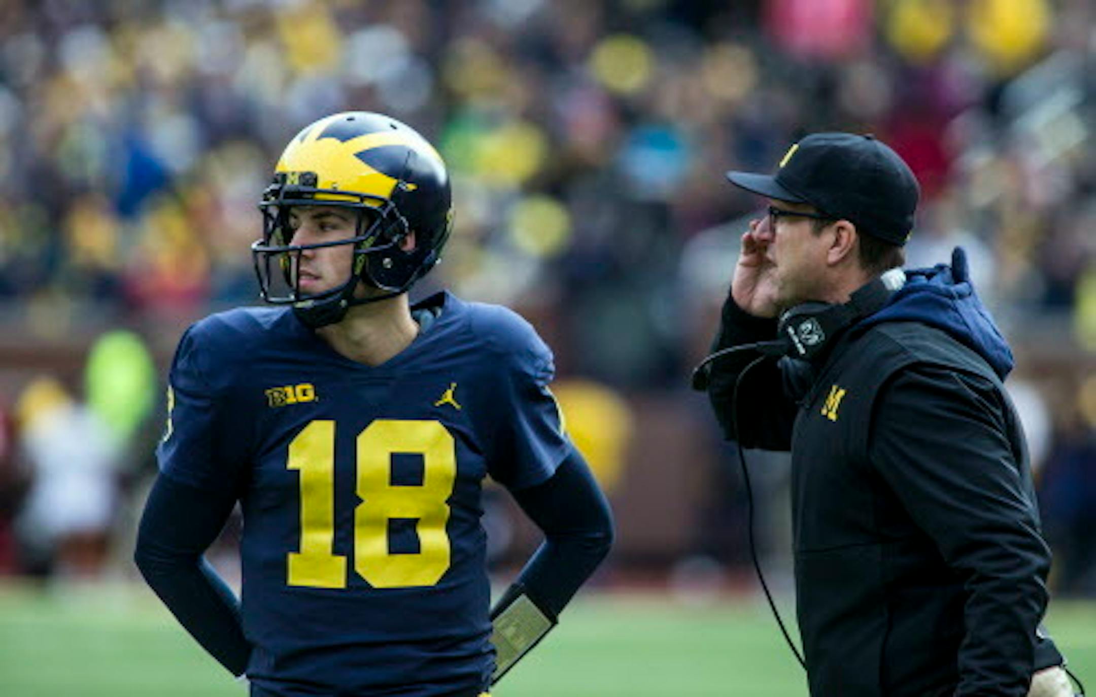 Michigan quarterback Brandon Peters (18) gets instructions from head coach Jim Harbaugh, right, between downs in the fourth quarter of an NCAA college football game against Rutgers in Ann Arbor, Mich., Saturday, Oct. 28, 2017. Michigan won 35-14. (AP Photo/Tony Ding)