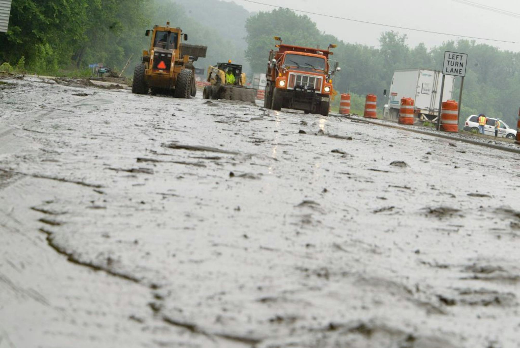 Jerry Holt/Star Tribune 6/9/2004---Crews remove mud and tree limbs in the south bound lanes of 169 just north of Mankato on Wednesday morning. The Highways south bound lane was closed due to mudslides.