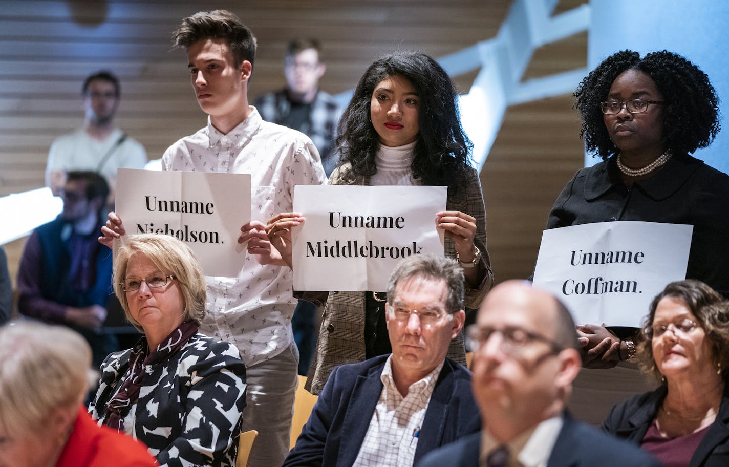 University of Minnesota students Ian Smith, from left, Chloe Williams and Jael Kerandi stand with signs during the vote. ] LEILA NAVIDI &#xa5; leila.navidi@startribune.com BACKGROUND INFORMATION: The University of Minnesota Board of Regents holds a special meeting to vote on keeping the current names of Coffman Union and three other campus buildings at McNamara Alumni Center on the campus of the University of Minnesota in Minneapolis on Friday, April 26, 2019. The board voted 10-1 against changi