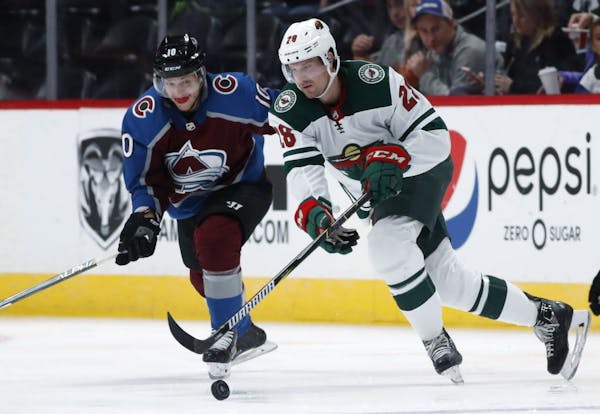 Minnesota Wild defenseman Alex Grant, front, reaches out for the puck as Colorado Avalanche right wing Sven Andrighetto defends in the third period of