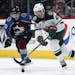 Minnesota Wild defenseman Alex Grant, front, reaches out for the puck as Colorado Avalanche right wing Sven Andrighetto defends in the third period of