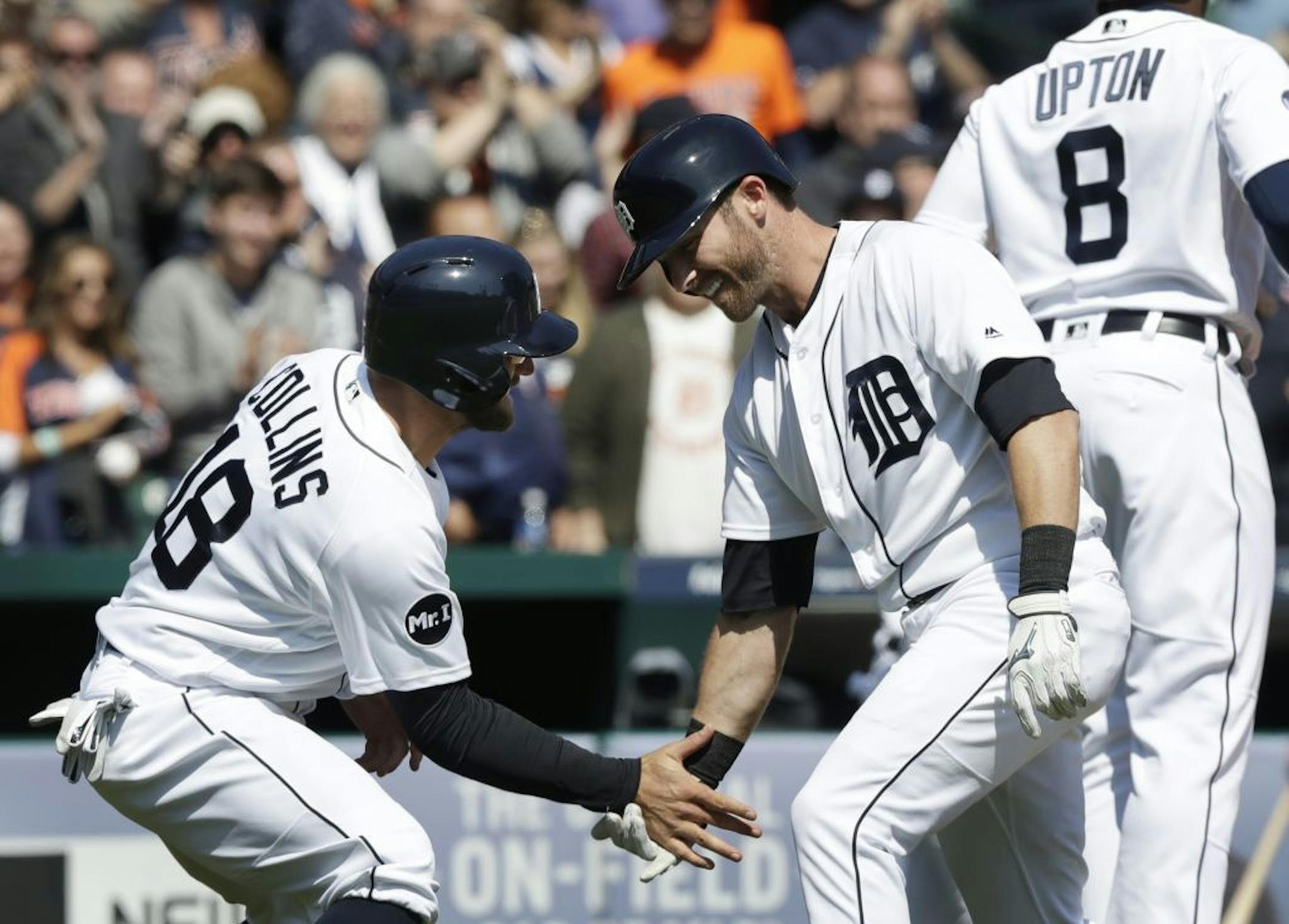 Detroit Tigers' Andrew Romine is greeted at home by Tyler Collins after a grand slam during the fourth inning of a baseball game against the Minnesota Twins, Wednesday, April 12, 2017, in Detroit.