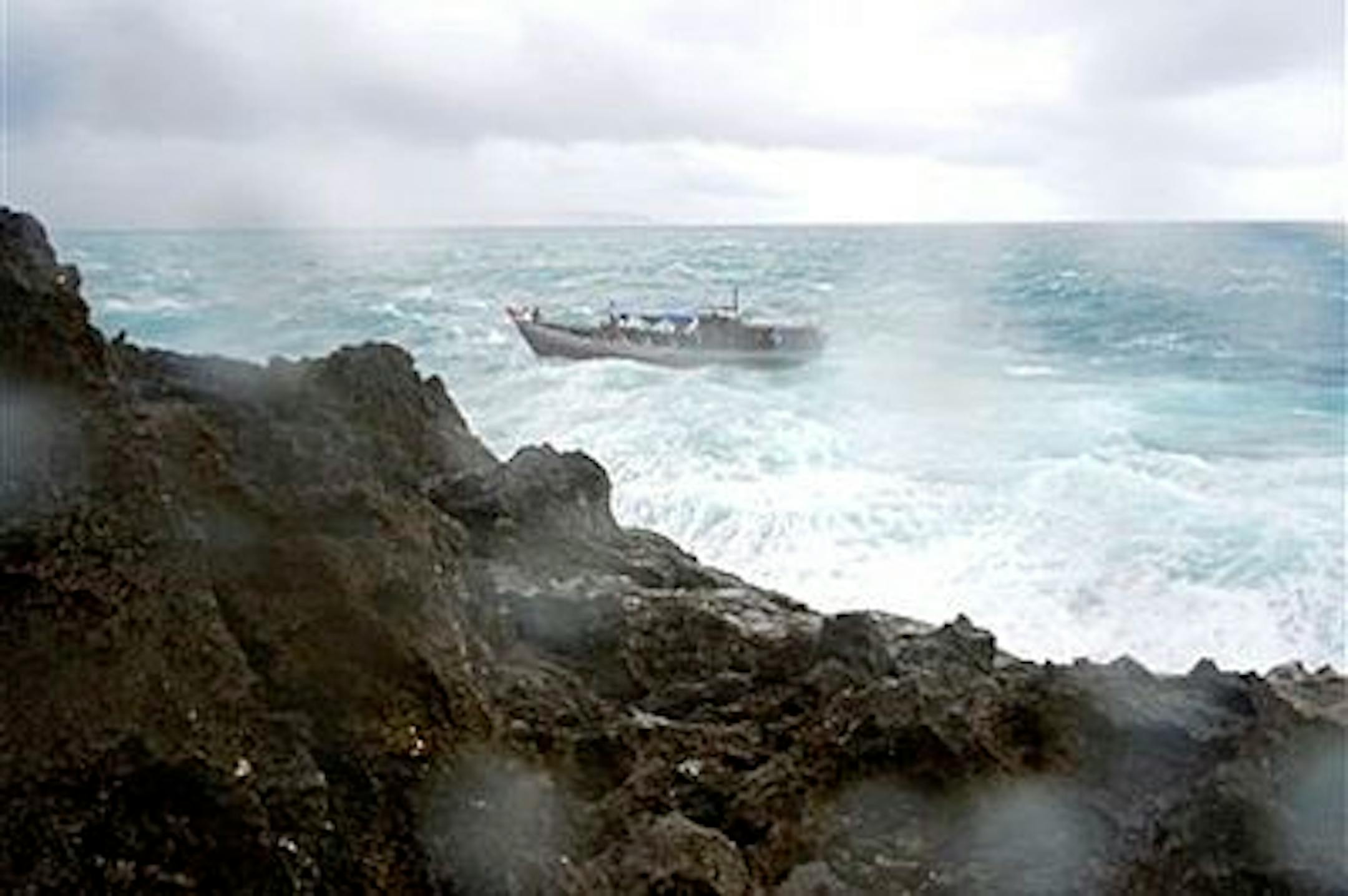 An asylum seeker boat approaches the rocky shore on Christmas Island just before it breaks up on the rocks Wednesday, Dec. 15, 2010. The wooden boat packed with dozens of asylum seekers smashed apart on cliff-side rocks in heavy seas off an Australian island Wednesday, sending some to their deaths in churning whitewater. (AP Photo/ABC) AUSTRALIA OUT