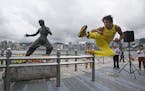 Chinese actor Mei Zhiyong dressing as the late Hong Kong Kung Fu star Bruce Lee performs in front of the bronze statue in Hong Kong Saturday, July 20,