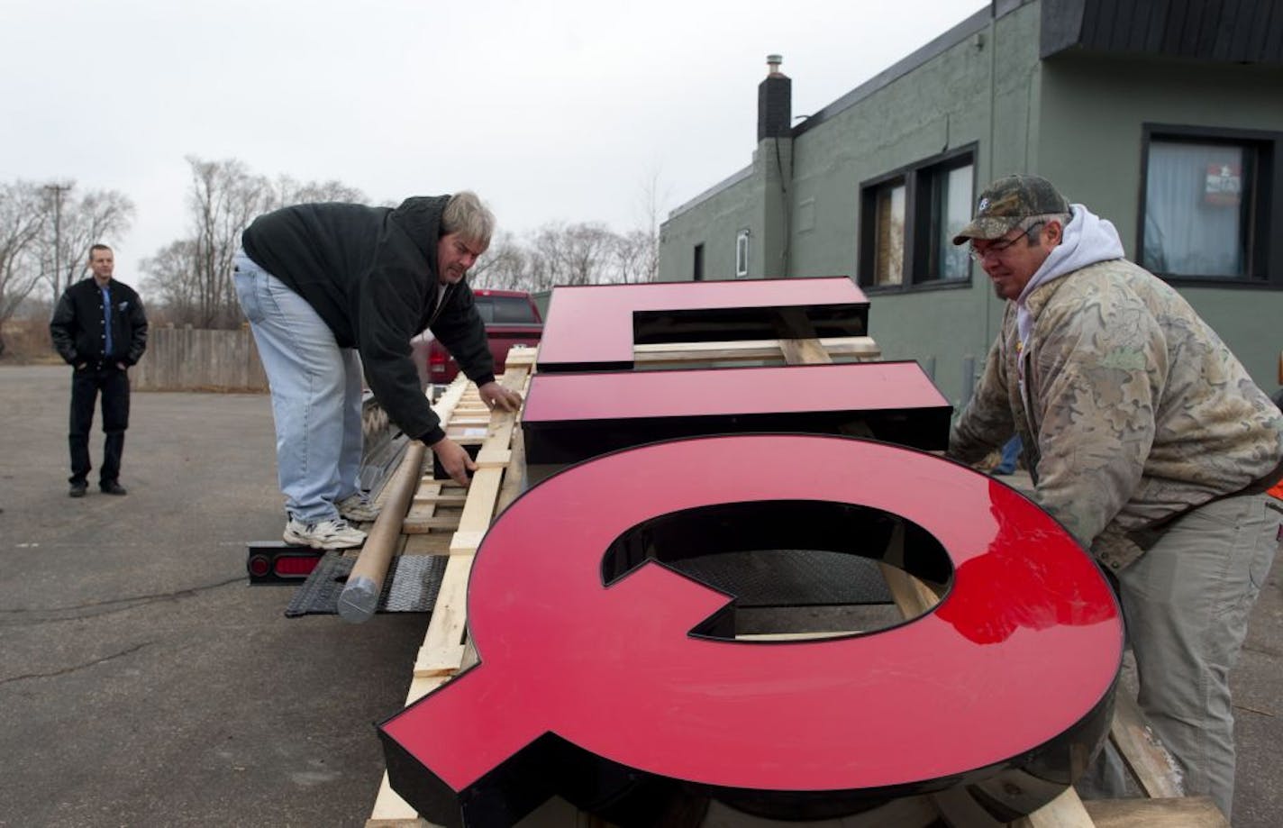 Richard "Jake" Jacobson, left, owner of Jake's Discount Liquors, in Coates, Minn. along Hwy. 52, watched as Jim Semon and Matt McCorkel delivered his new sign Wednesday morning. The building, formerly Jake's Gentleman's Club which he was forced to close nine years ago. Jacobson's new liquor store which opened officially today, November 23, 2011