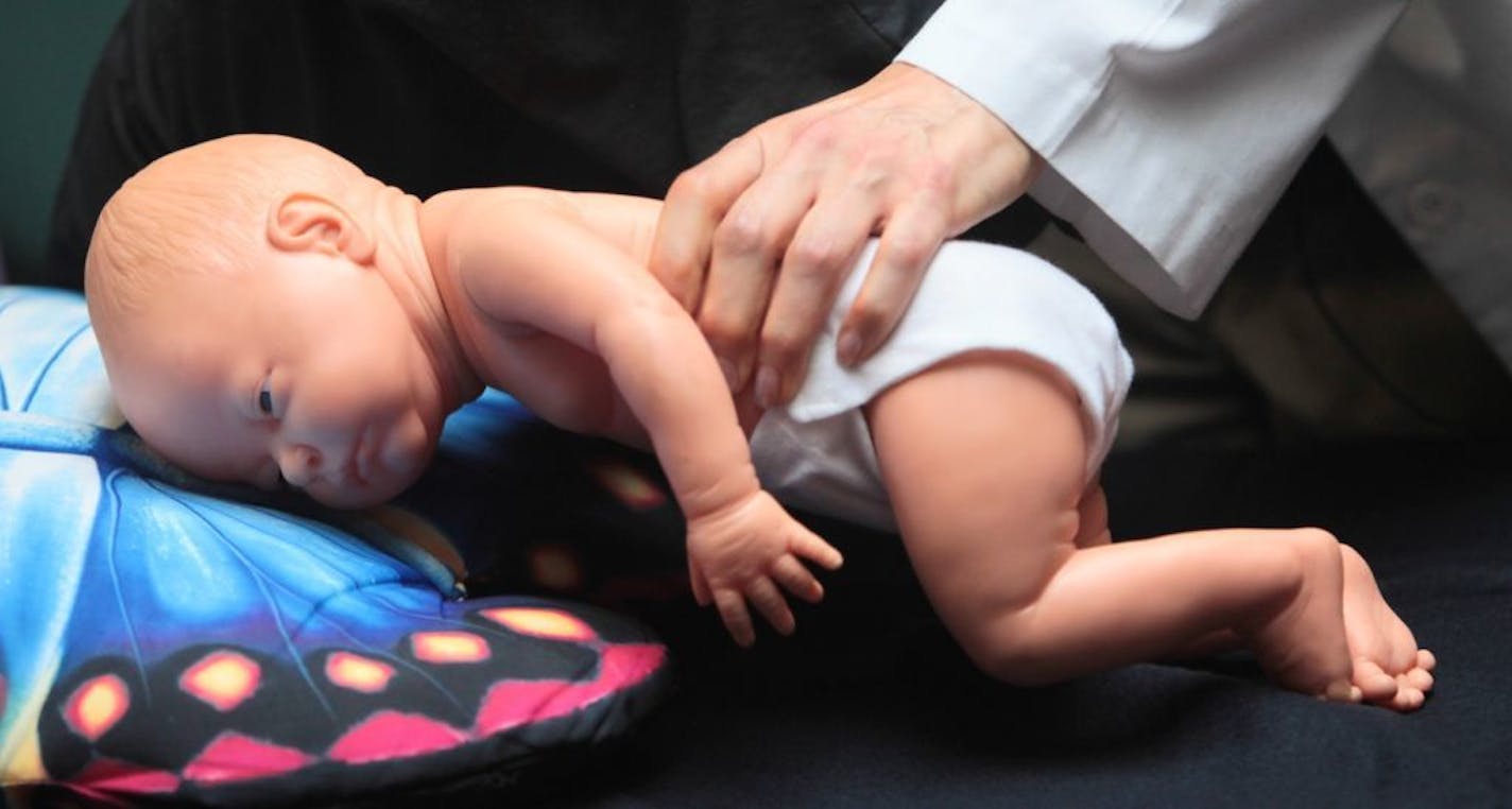 In this photo taken March 22, 2012, Dr. Wendy Gunther demonstrates how an infant can die due to unsafe sleeping practices using a scene re-enactment doll that has helped them separate sleeping deaths from SIDS deaths, or sudden infant death syndrome, in Norfolk, Va.