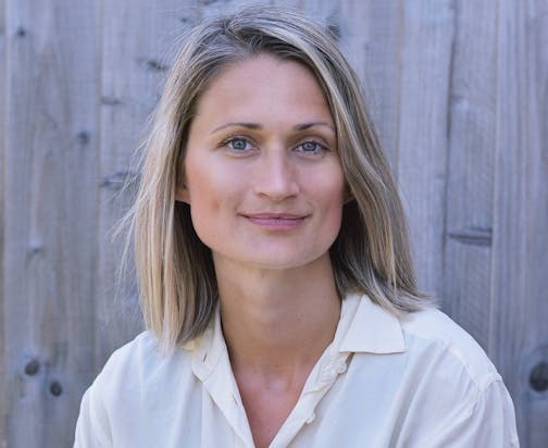photo of author Emma Stonex in front of a gray siding wall
