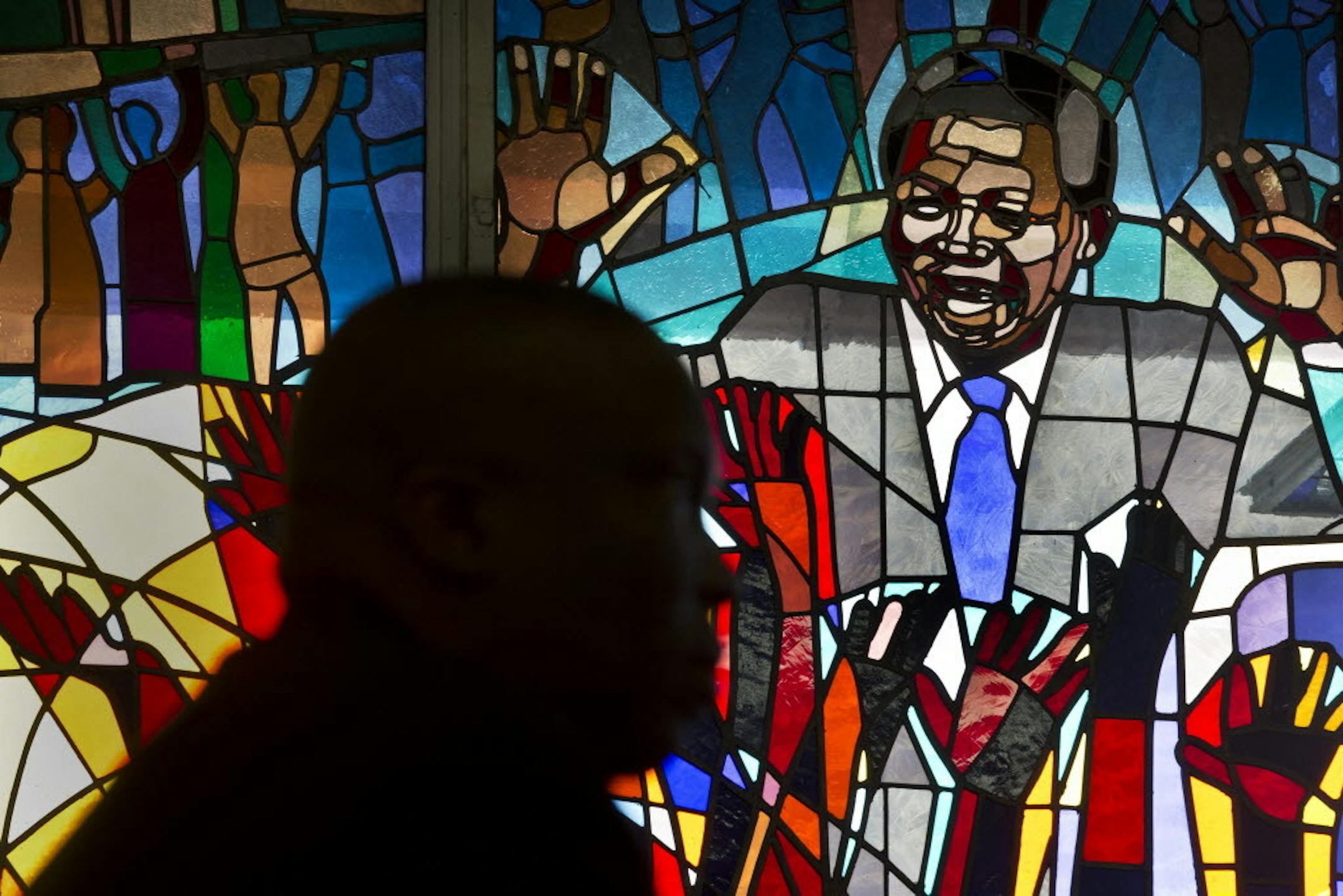 Sunday, Dec. 8, 2013: A mourner is silhouetted in front of a stained-glass window of Nelson Mandela at the Regina Mundi church, which became one of the focal points of the anti-apartheid struggle, in Soweto, Johannesburg, South Africa