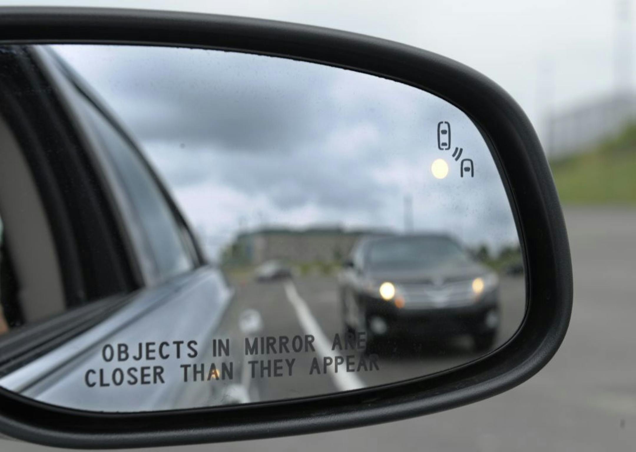 In this photo taken Tuesday, May 22, 2012, professional test driver J.D. Ellis of Cincinnati, Ohio, demonstrates the side mirror warning signal in a Ford Taurus at an automobile testing area in Oxon Hill, Md. The display at a recent transportation conference was a peek into the future of automotive safety: cars that to talk to each other and warn drivers of impending collisions. Later this summer, the government is launching a yearlong, real-world test involving nearly 3,000 cars, trucks and bus