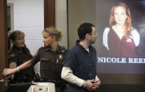 Larry Nassar is escorted into the courtroom past a photograph of one of his victims , Friday, Jan. 19, 2018, in Lansing, Mich., during the fourth day 