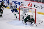 Minnesota Wild goalie Cam Talbot, right, stops a shot as Wild defenseman Jared Spurgeon (46) and Vancouver Canucks right wing Vasily Podkolzin, second