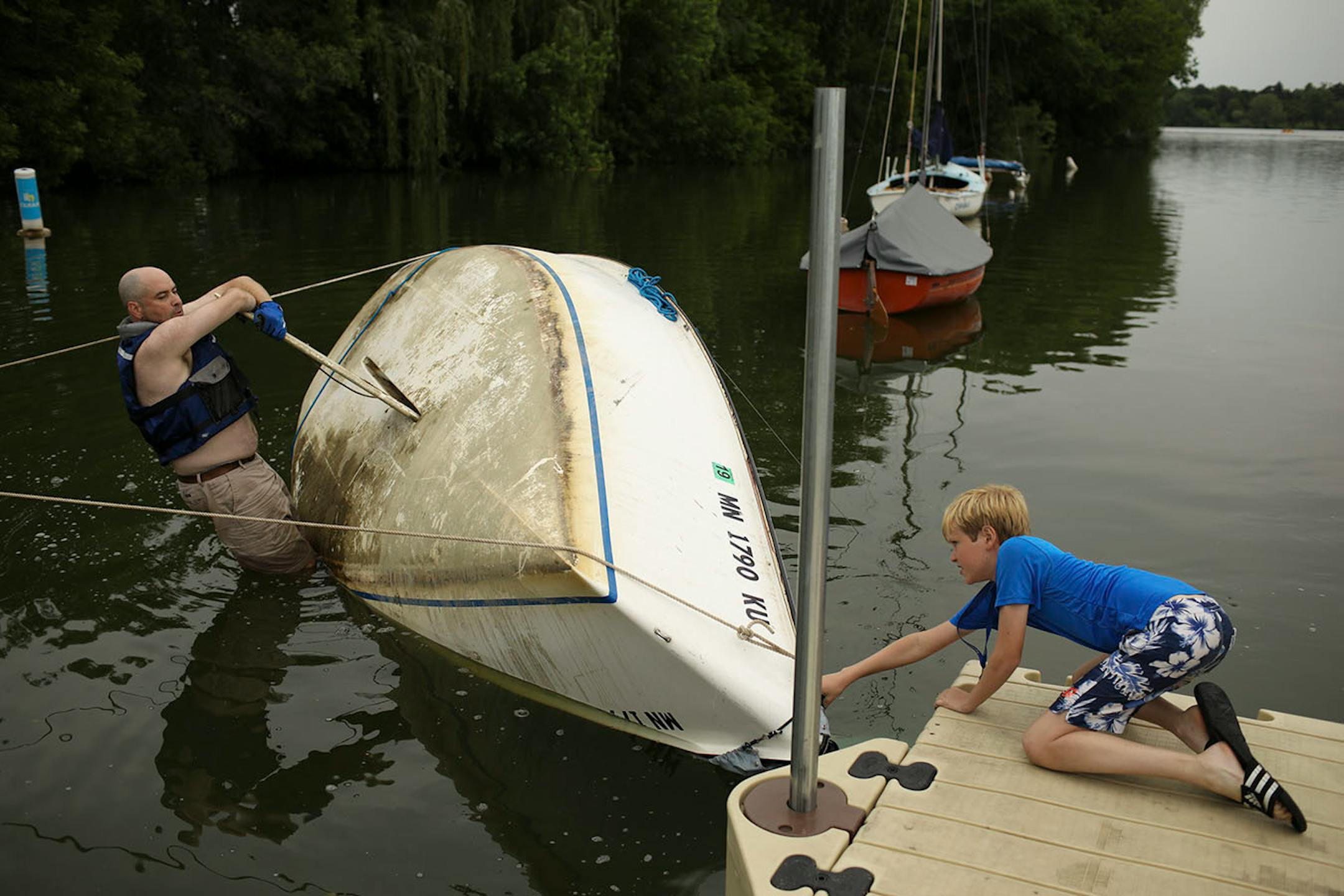 Martin Conroy and his son, James, 12, waited for some help from others as they attempted to right his overturned sailboat on Lake Nokomis Sunday afternoon. When he drove past the lake after the storm Sunday morning, "I saw that I was the only one flipped, so I went home and changed for my unplanned afternoon adventure."
