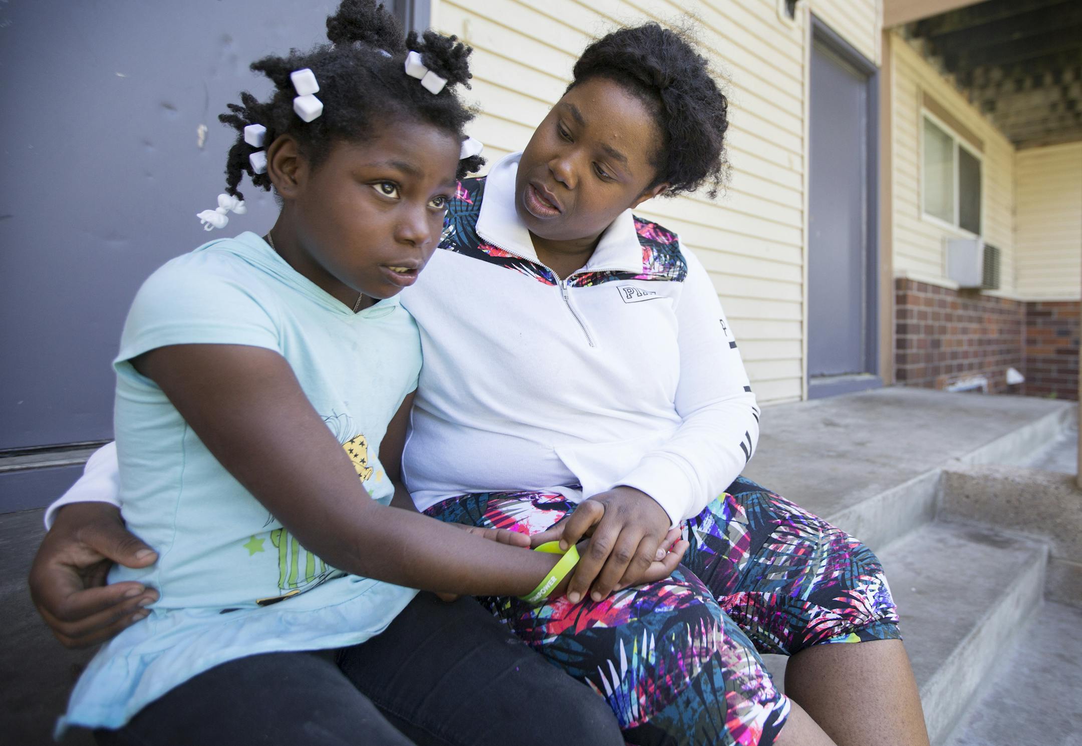 Jon'tayasia Dillon-White, 10, and her mother Tequila Dillon sit outside their home on N. Plymouth Avenue in Minneapolis. ] (Leila Navidi/Star Tribune) leila.navidi@startribune.com BACKGROUND INFORMATION: Tuesday, June 7, 2016 in Minneapolis. Jon'tayasia Dillon-White, 10, was shot in the foot by a stray bullet that came through her bedroom wall from the alley during a shooting on May 5. There is a GoFundMe account set up for mother Tequila Dillon to move out of the crime-plagued neighborhood.