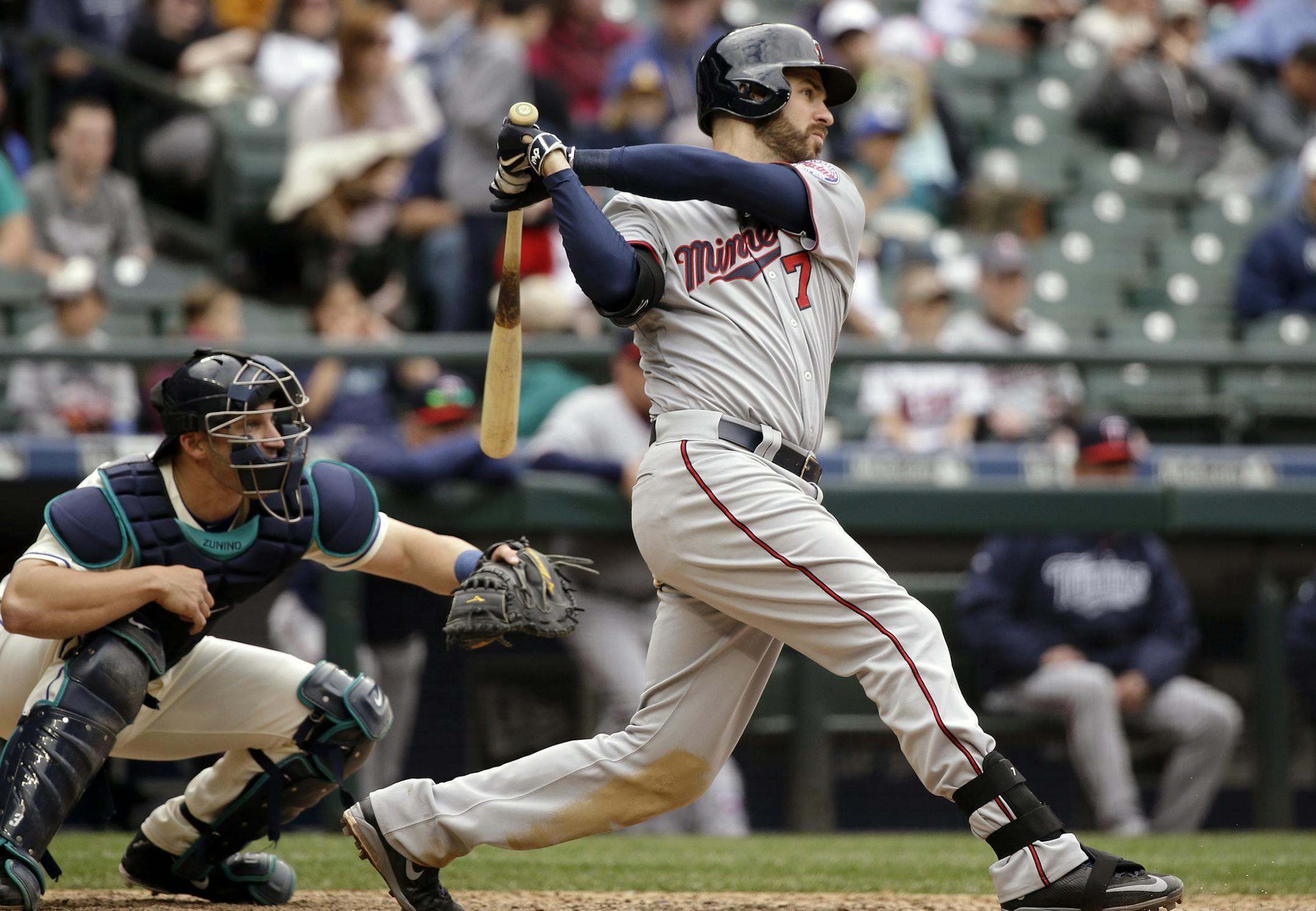 Minnesota Twins' Joe Mauer, right, hits a triple to drive in a pair of runs as Seattle Mariners catcher Mike Zunino looks on in the 11th inning of a baseball game Sunday, April 26, 2015, in Seattle. (AP Photo/Elaine Thompson)