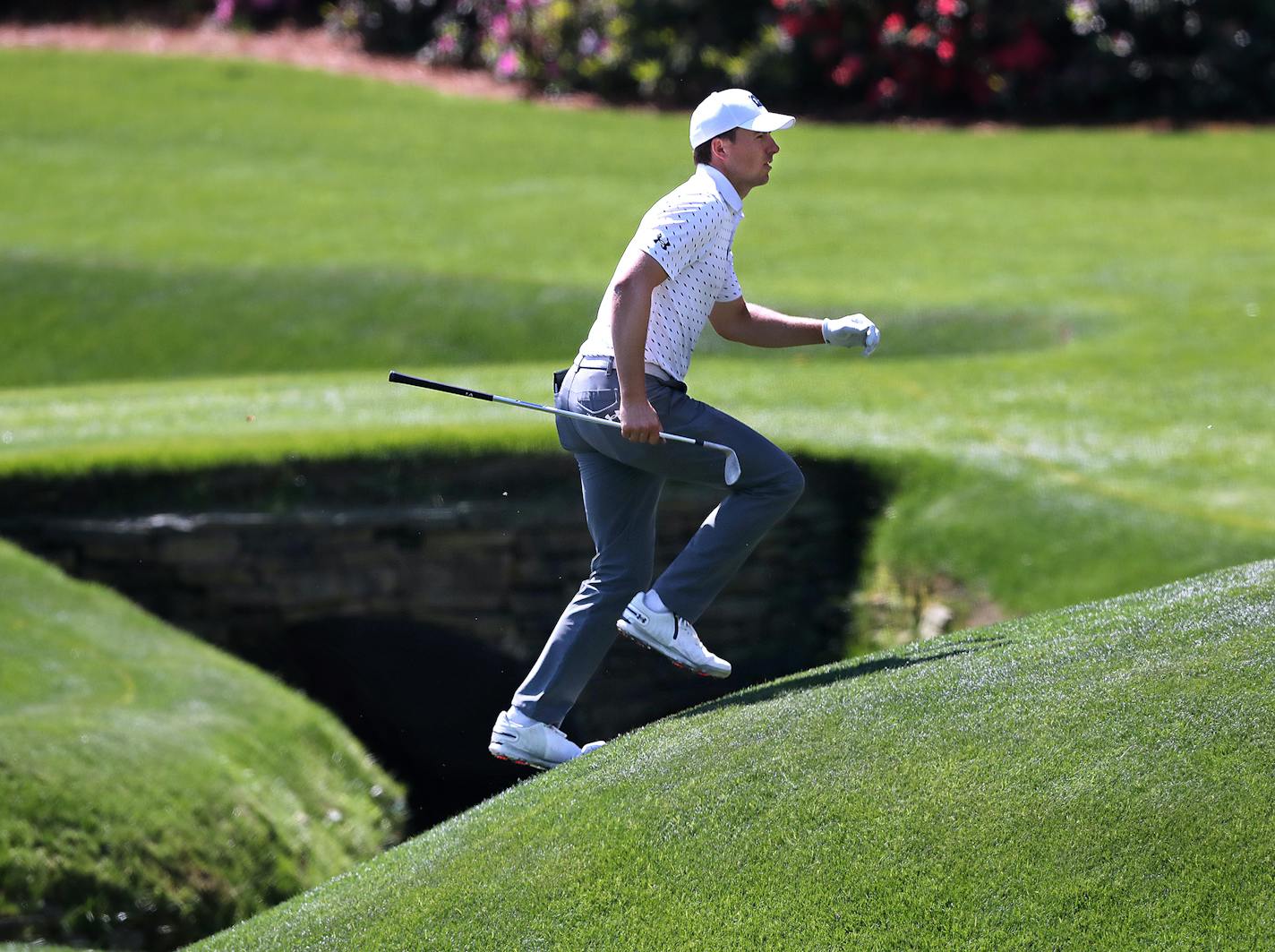 Jordan Spieth runs across the tributary to Rae's Creek to the 13th green during his practice round for the Masters at Augusta National Golf Club.