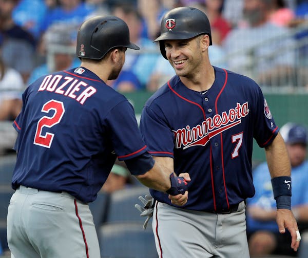 Minnesota Twins' Brian Dozier congratulates teammate Joe Mauer after Mauer scored on a single by Eddie Rosario in July. Mauer retired on Friday.