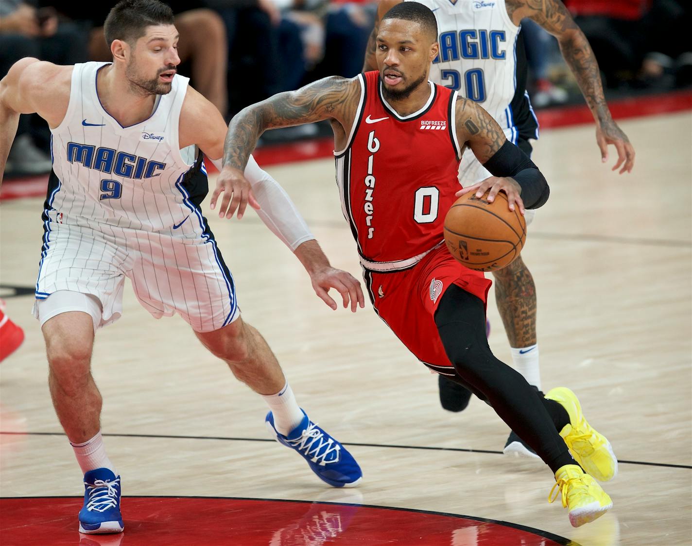 Portland Trail Blazers guard Damian Lillard, right, dribbles past Orlando Magic center Nikola Vucevic during the second half of an NBA basketball game in Portland, Ore., Friday, Dec. 20, 2019. (AP Photo/Craig Mitchelldyer)