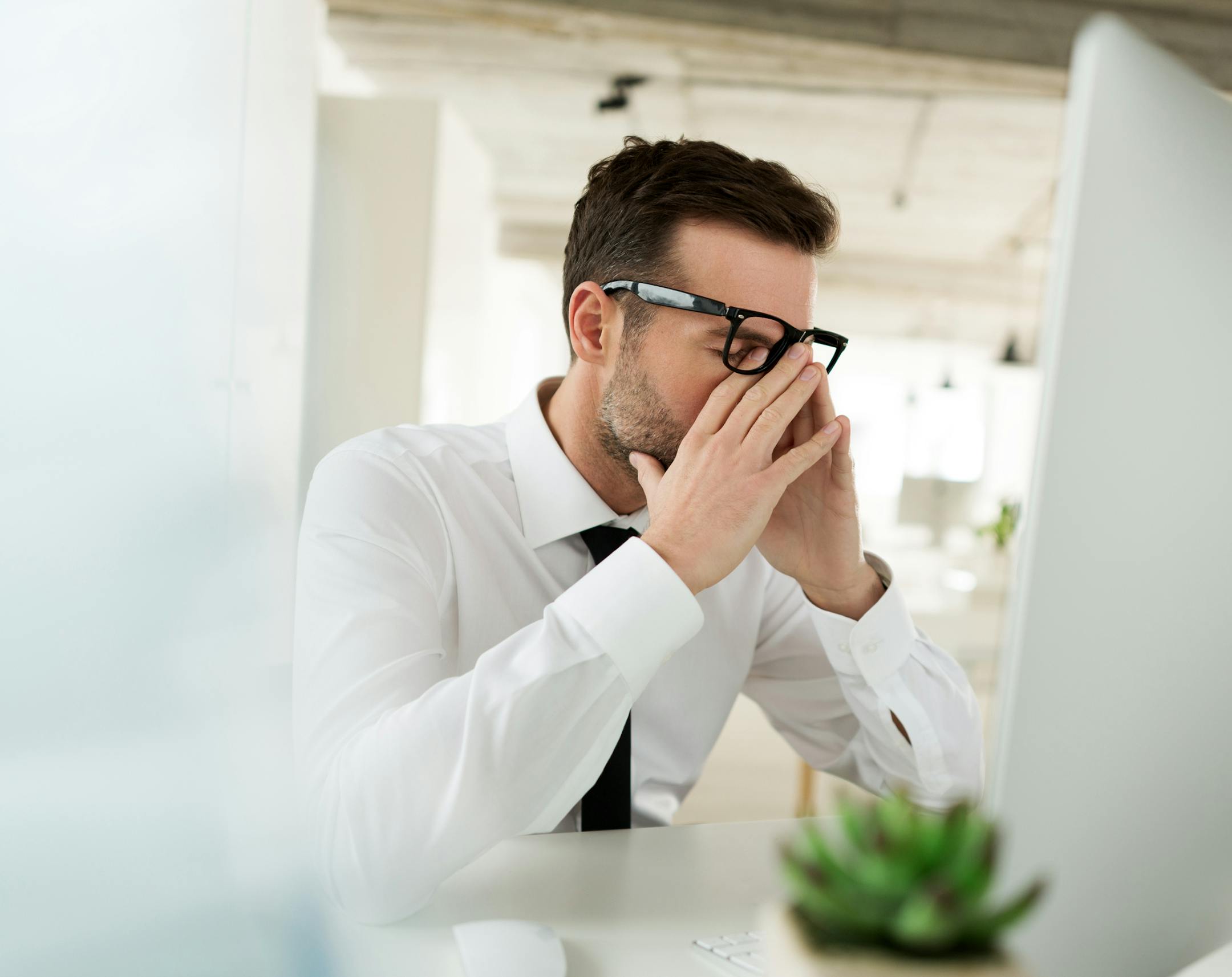 Worried businessman sitting at the desk in his office and using computer.