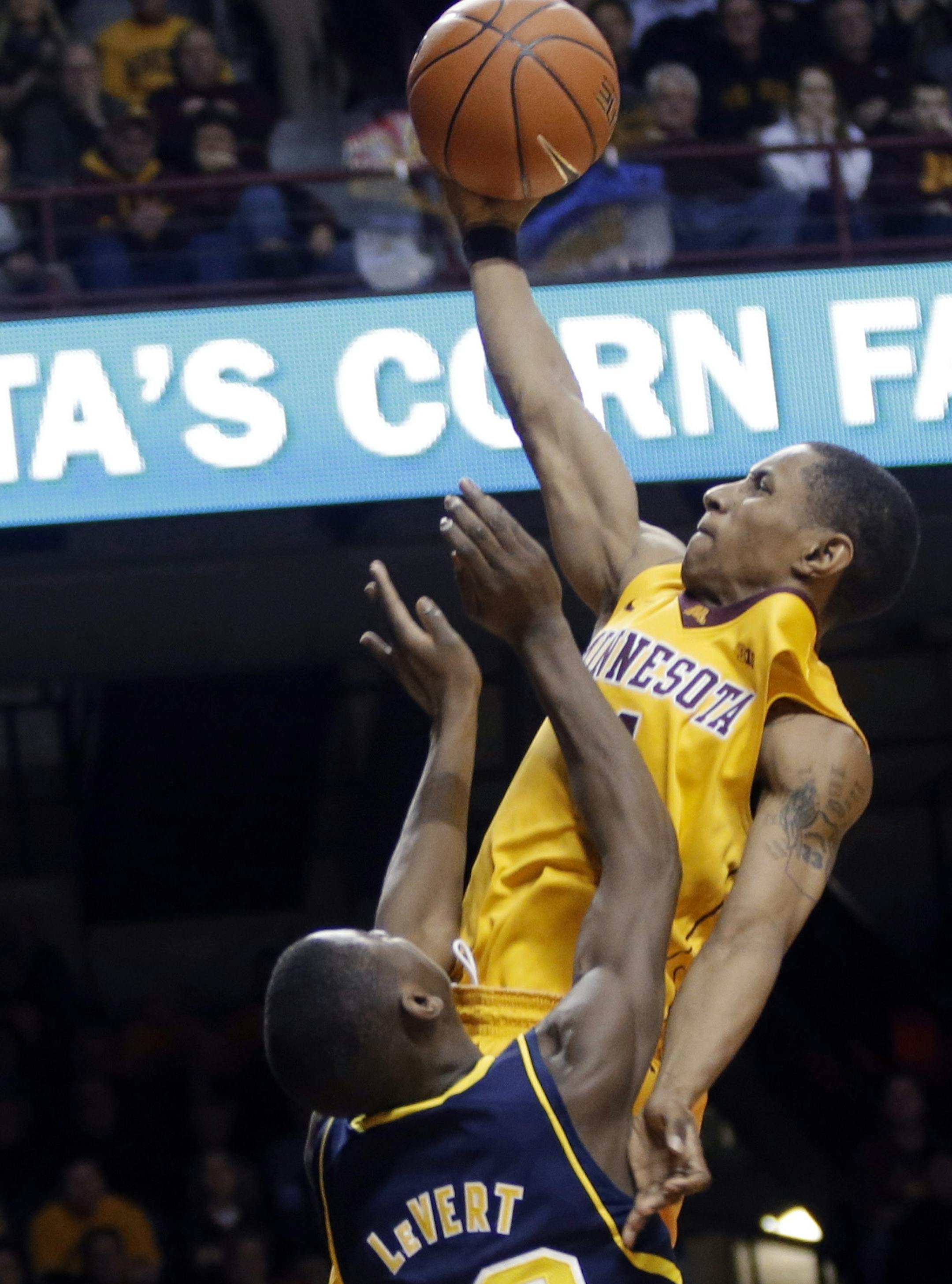 Minnesota's Deandre Mathieu, top, lays up a shot as Michigan's Caris LeVert defends during the second half of an NCAA college basketball game Thursday, Jan. 2, 2014, in Minneapolis. Michigan won 63-60. (AP Photo/Jim Mone)
