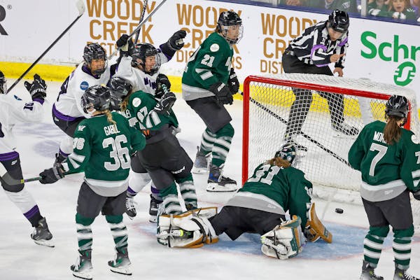 Minnesota forward Liz Schepers, center, raises her arms in celebration after scoring as Boston goalie Aerie Frankel (31) looks at the puck in the net 