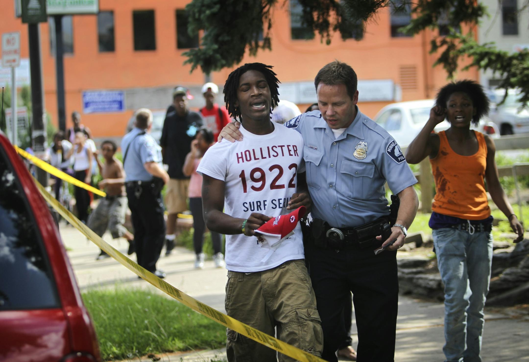 A Minneapolis police officer comforts a man who identified himself as a brother to the shooting victim in the 2900 block of Bloomington Ave. S. Friday, June 1, 2012. The victim had left the scene.