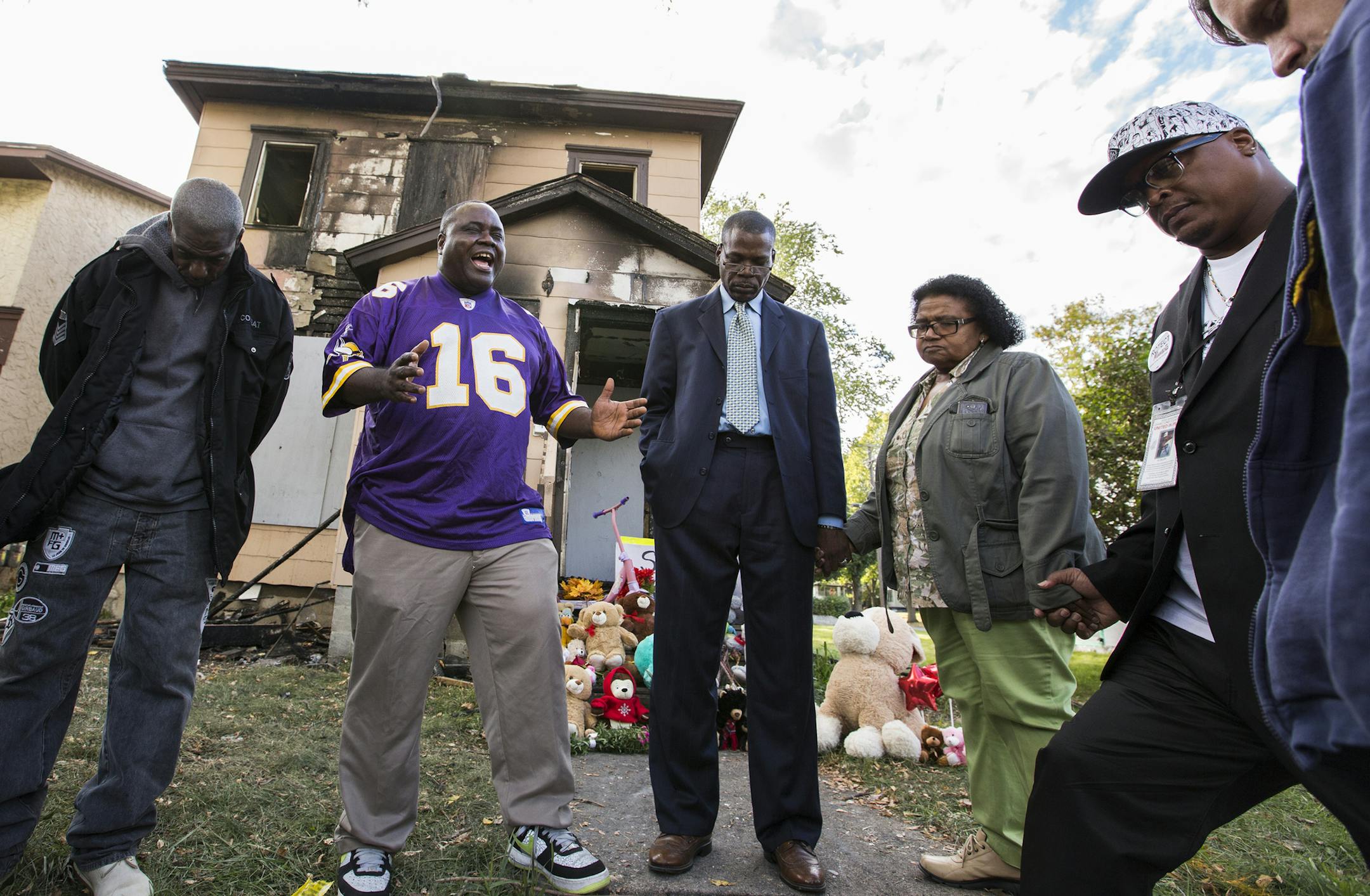Pastor Harding Smith, in purple, of the Spiritual Church of God leads a prayer in front of the Penn Avenue home where three children perished in a fire the night before in Minneapolis on Sunday, October 4, 2015. ] LEILA NAVIDI leila.navidi@startribune.com / BACKGROUND INFORMATION: Three young children died in a late-night fire October 3, 2015 in a house in north Minneapolis&#x2019; Jordan neighborhood that was without heat, the property owner said. One of the home&#x2019;s occupants, later deter