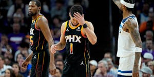 Suns guard Devin Booker (1) rubs his forehead after a three pointer by Wolves guard Nickeil Alexander-Walker on Friday night.