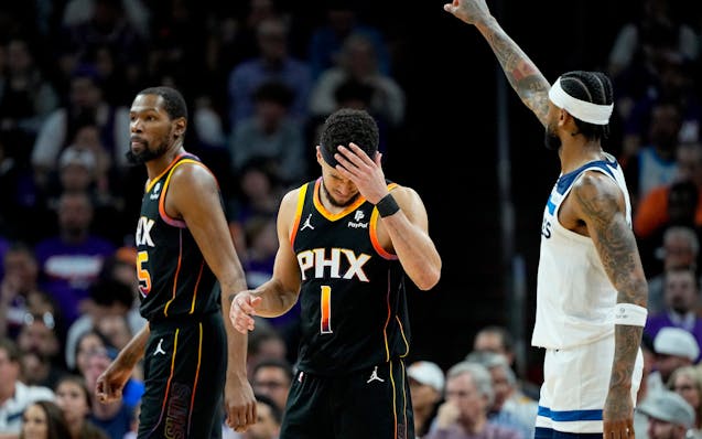 Suns guard Devin Booker (1) rubs his forehead after a three pointer by Wolves guard Nickeil Alexander-Walker on Friday night.