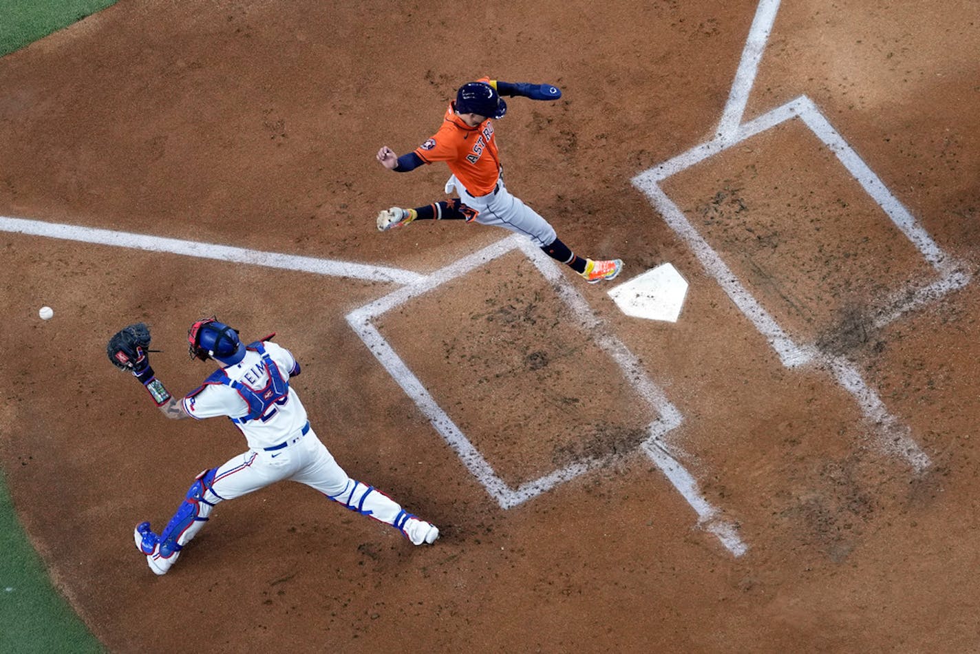 Houston Astros center fielder Mauricio Dubon, right, scores as Texas Rangers catcher Jonah Heim reaches for the throw during the second inning in Game 3 of the baseball American League Championship Series Wednesday, Oct. 18, 2023, in Arlington, Texas. (AP Photo/Godofredo A. Vasquez)