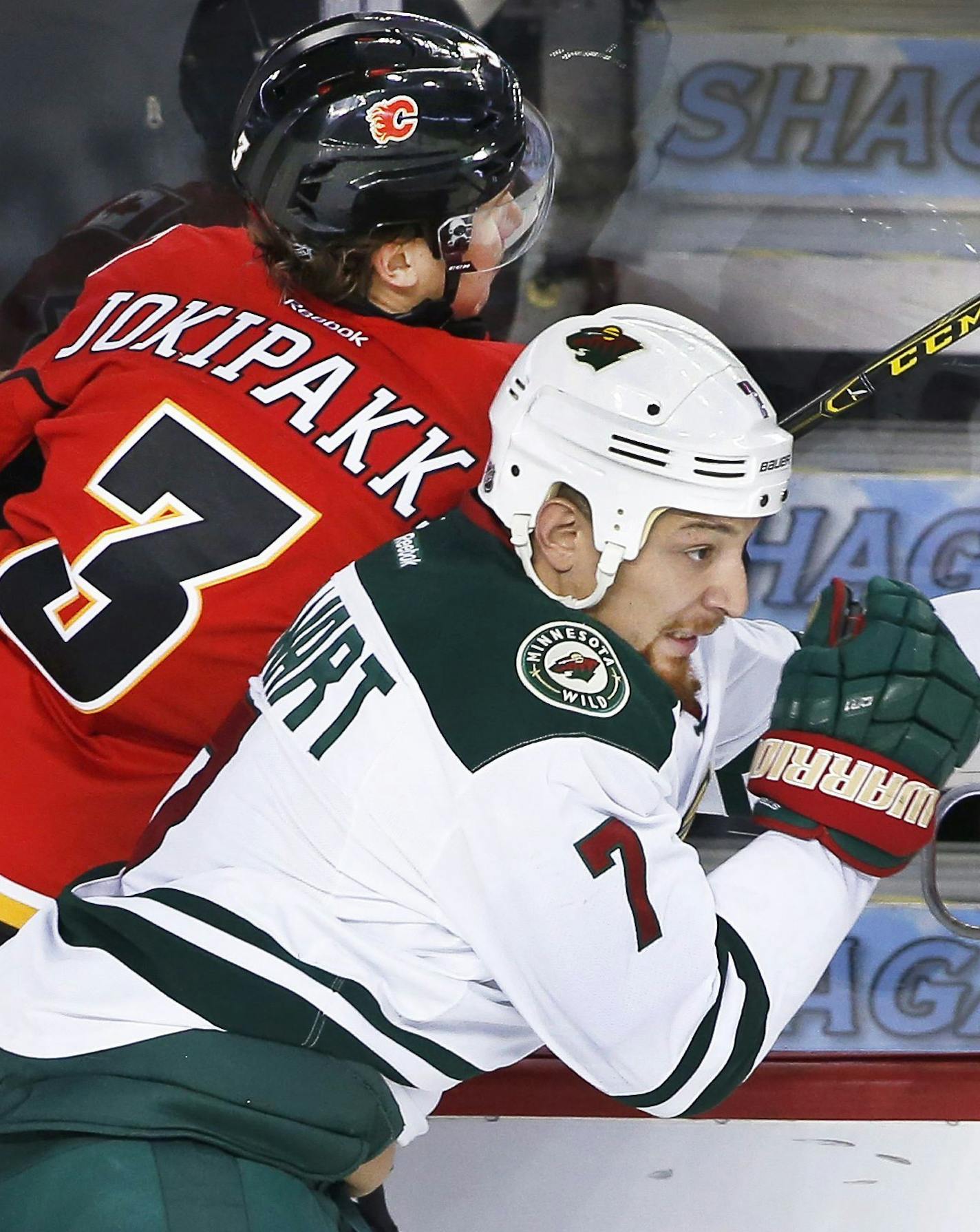 Minnesota Wild's Chris Stewart, right, checks Calgary Flames' Jyrki Jokipakka, from Finland, during second-period NHL hockey game action in Calgary, Alberta, Friday, Dec. 2, 2016. (Larry MacDougal/The Canadian Press via AP)