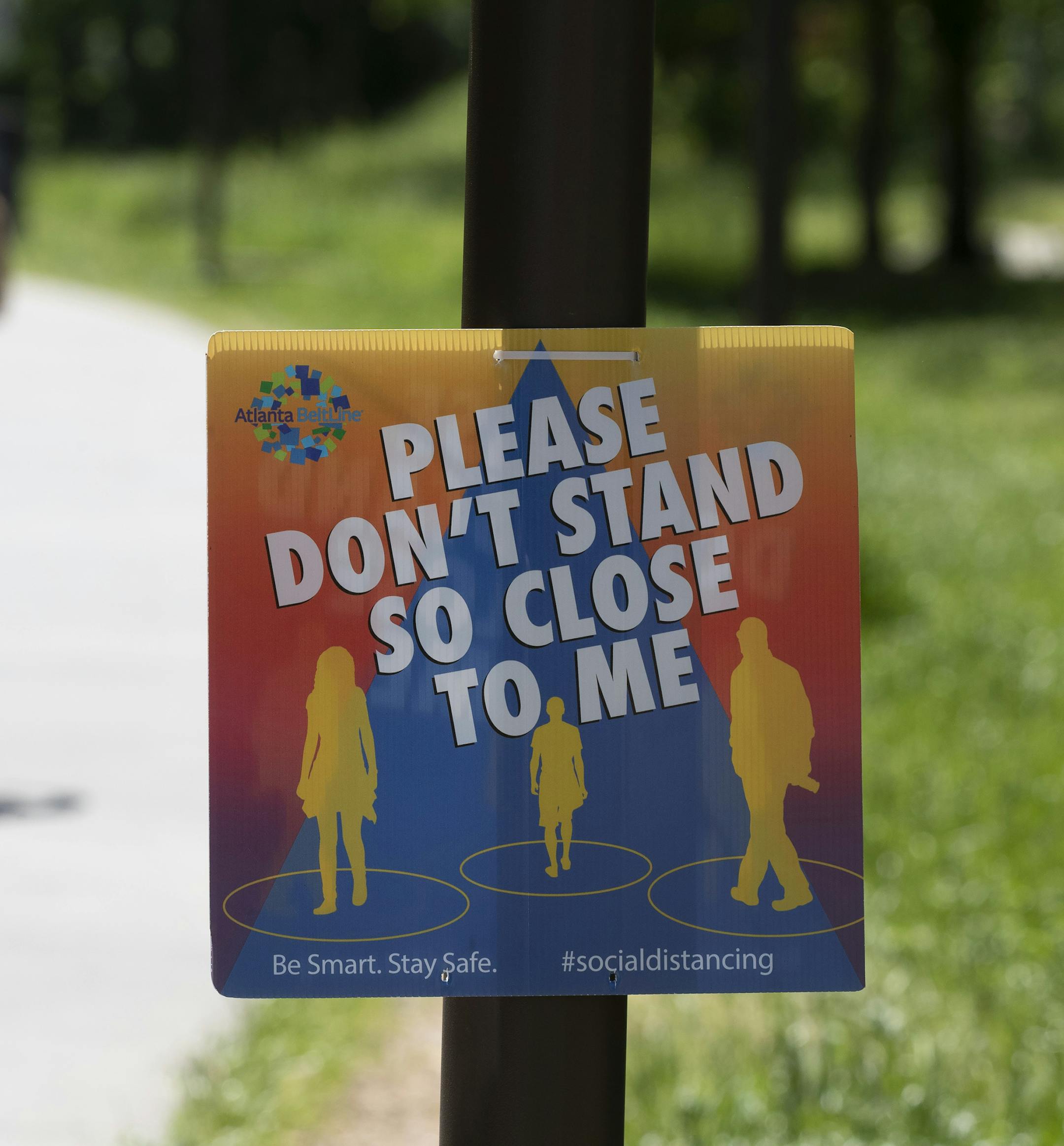 A sign asked people to maintain social distance as they enjoy the warm weather on the Beltline in Atlanta's Inman Park neighborhood Friday, May 1, 2020. Georgia shelter in place order expired Thursday and was not renewed for most Georgians by Gov. Brian Kemp. (AP Photo/John Bazemore)