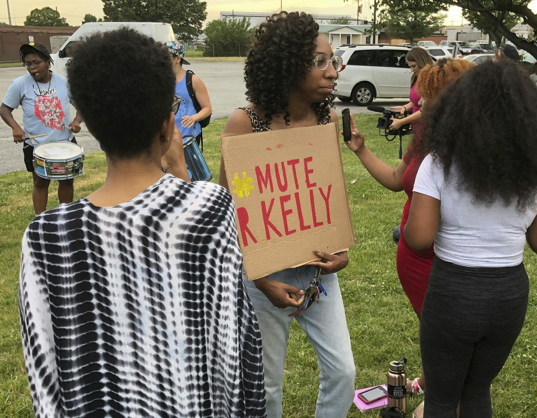 A protester carries a sign prior to a concert featuring R. Kelly in Greensboro, N.C., Friday, May 11, 2018. The group was demonstrating to protest Kelly's appearance in light of longstanding allegations of sexual misconduct and the decision by coliseum officials to proceed with the concert. Kelly denies abusing anyone and faces no current criminal charges. (AP Photo/Skip Foreman)