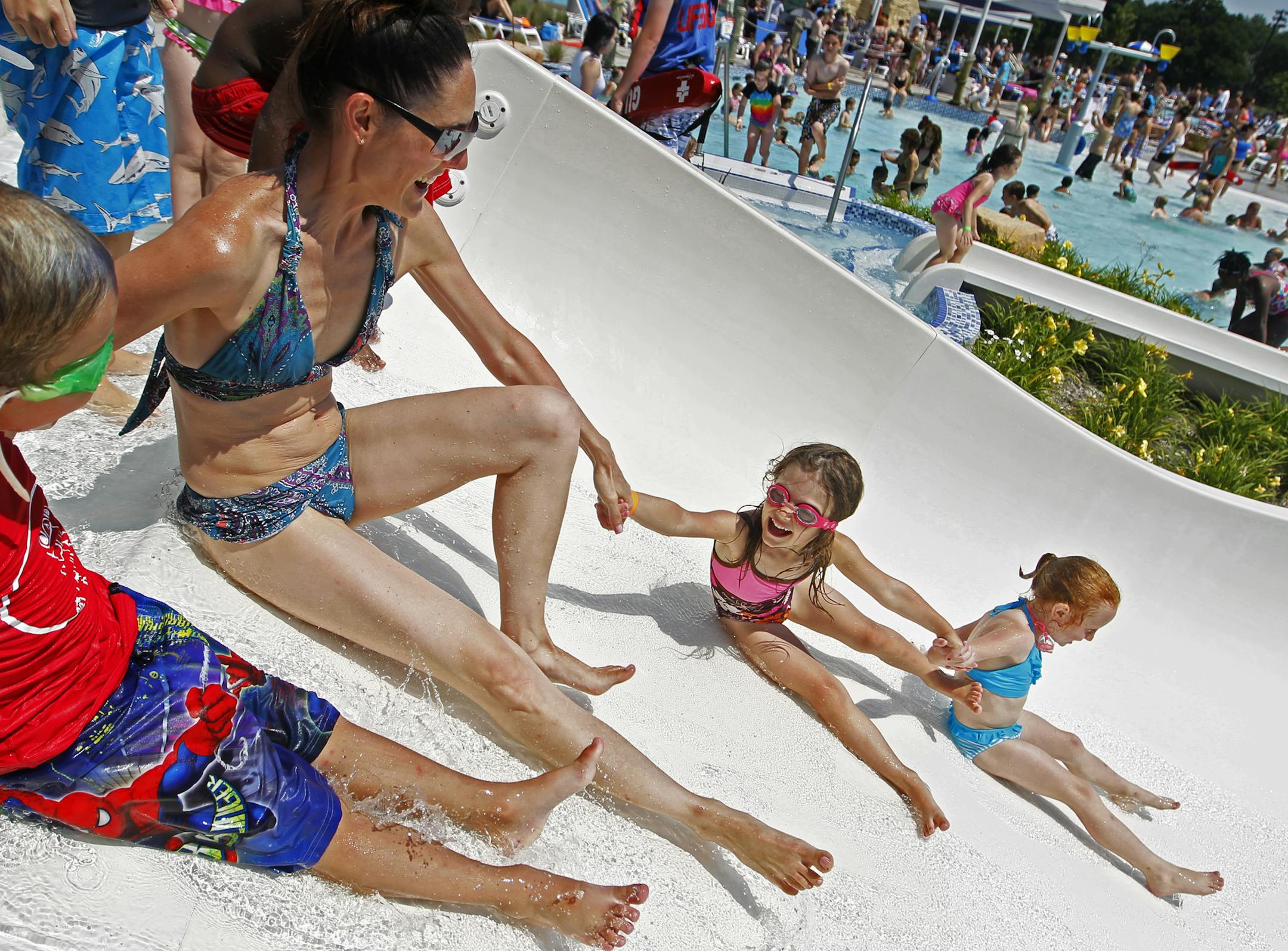 At the Como Park pool in St. Paul, Layne Gillitzer,6, joined his mother, Chris, sister Juells(cq),5, and friend Schanley Hunter,5, down the water slide to the refreshing pool below.] rtsong-taatarii@startribune.com