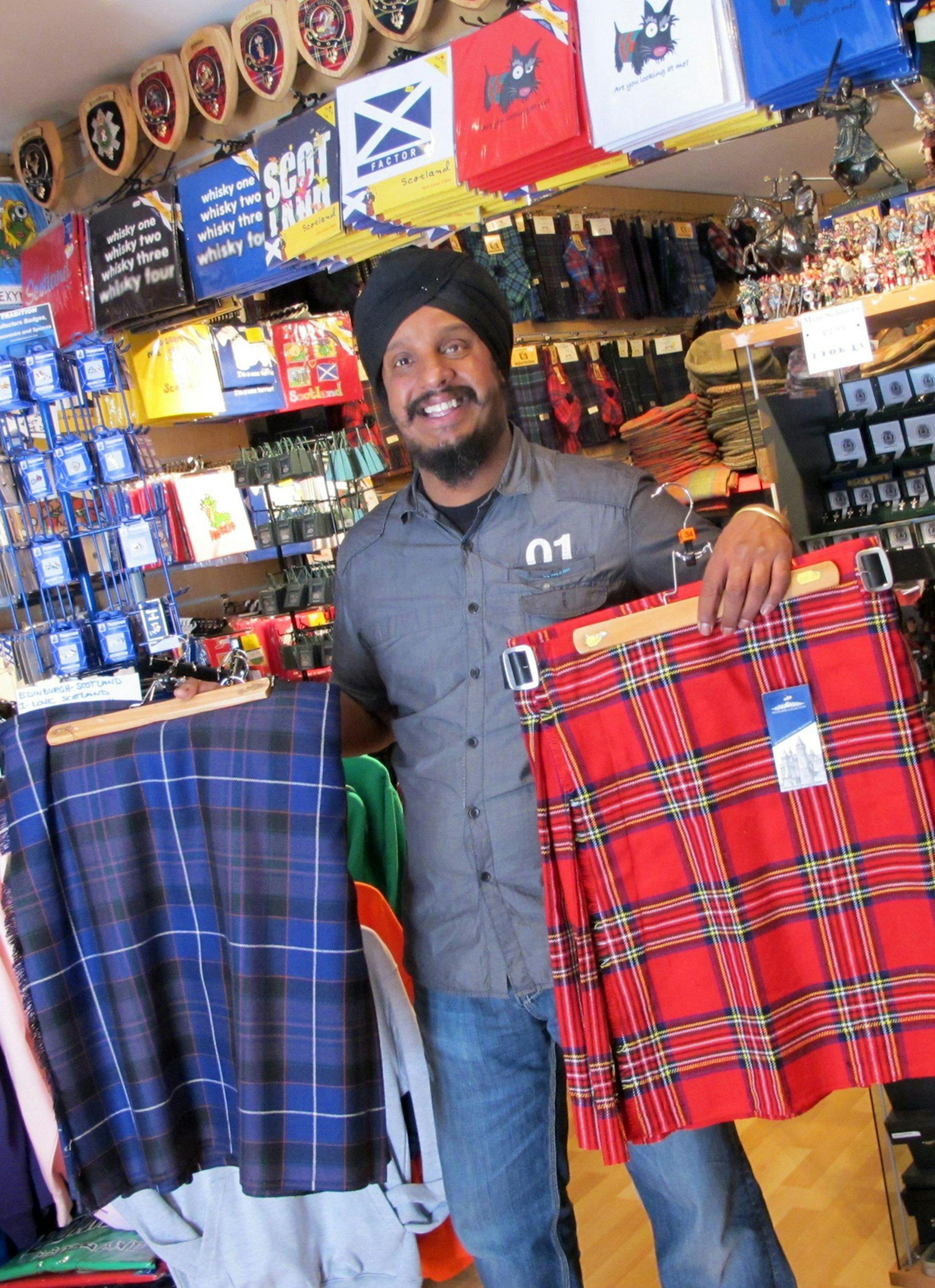 Sam Singh, manager of the Prestige Scotland shop on the Royal Mile in Edinburgh, defends selling cheap kilts and says they still can be called kilts, even if not made in Scotland. The red kilt is about $45 and the blue, made in Scotland, is about $400.