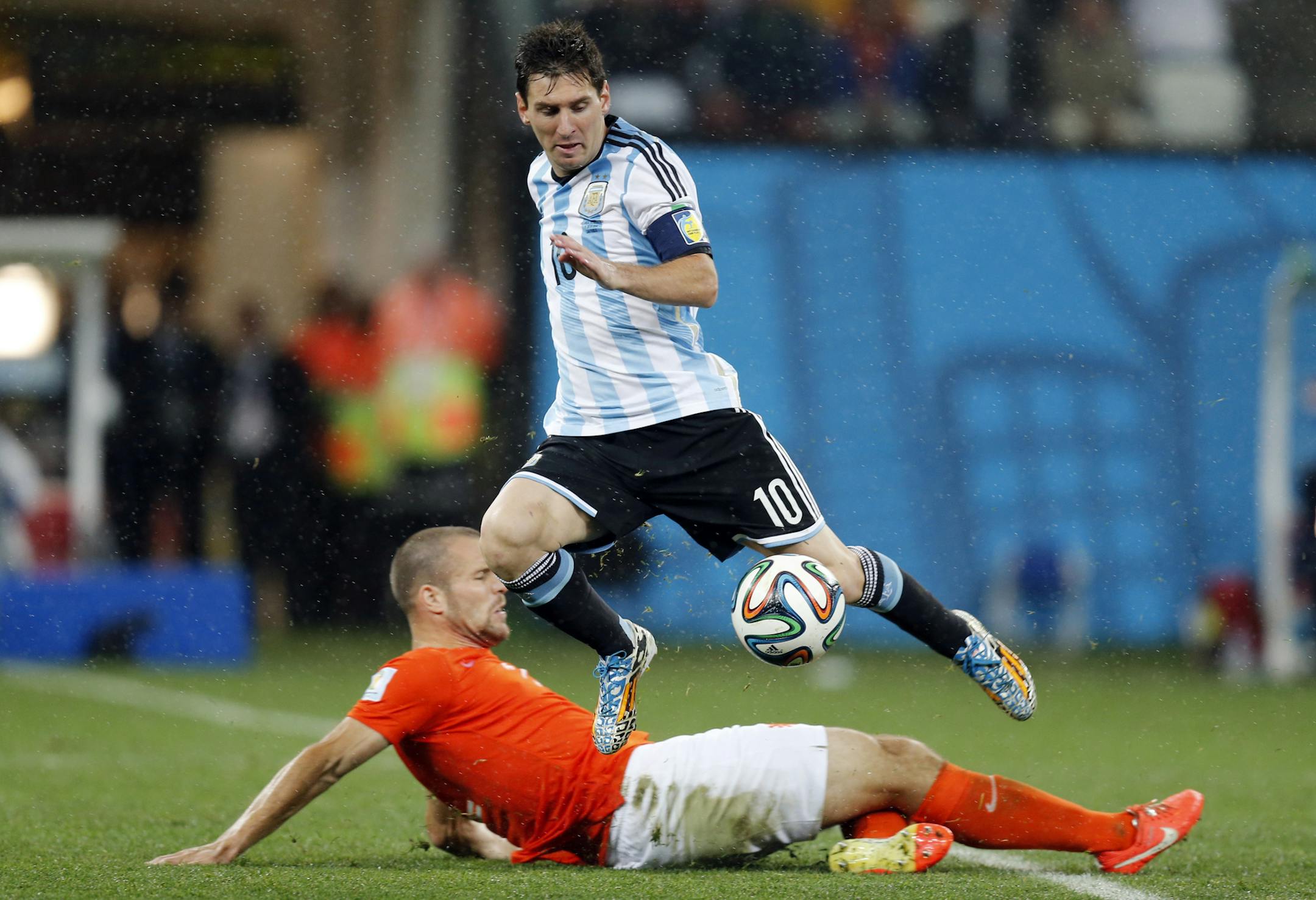 Netherlands' Ron Vlaar, bottom, tackles Argentina's Lionel Messi during the World Cup semifinal soccer match between the Netherlands and Argentina at the Itaquerao Stadium in Sao Paulo, Brazil, Wednesday, July 9, 2014. (AP Photo/Frank Augstein)