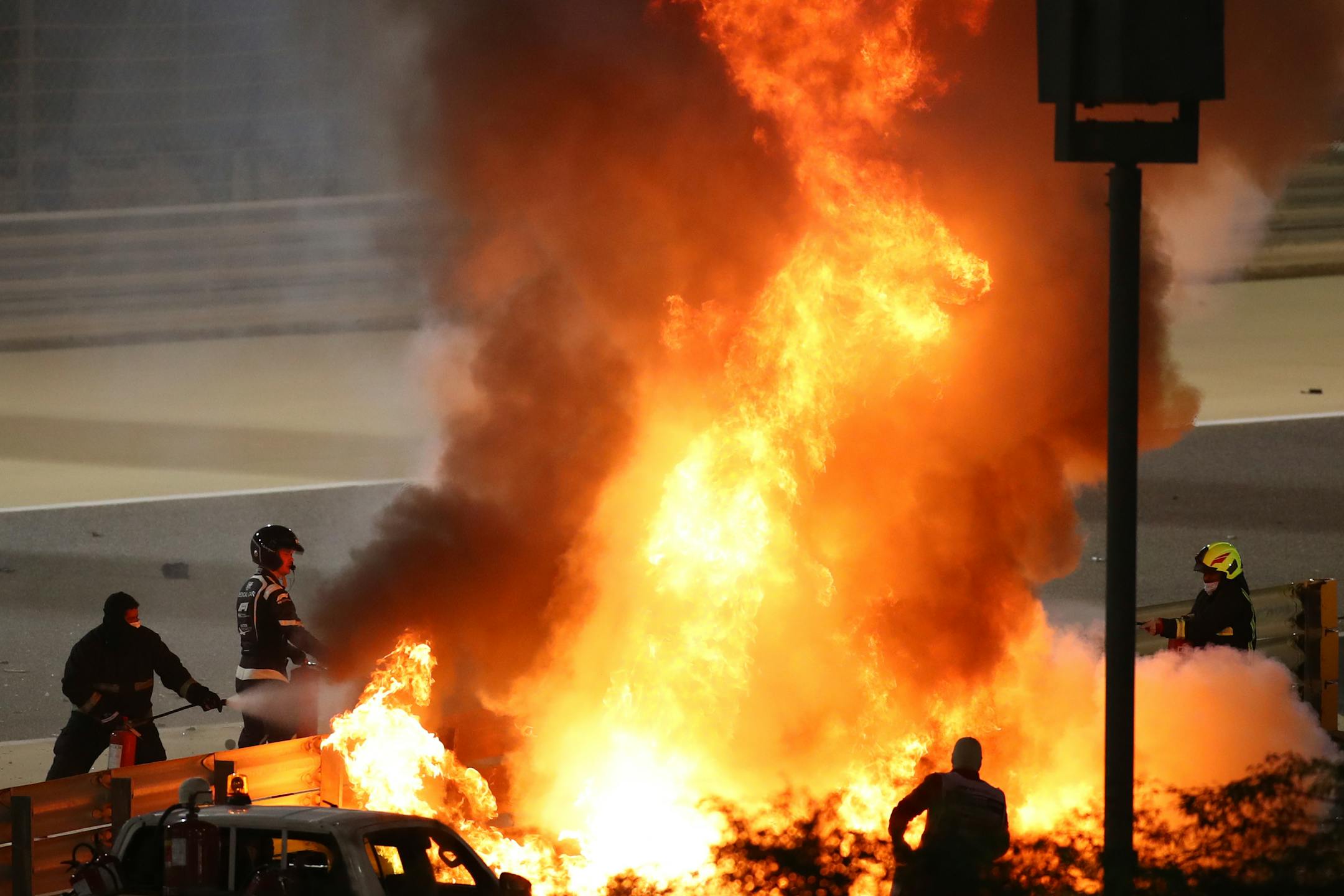 Staff extinguish flames from Haas driver Romain Grosjean's car after a crash during the Formula One race in Bahrain International Circuit in Sakhir, Bahrain, Sunday