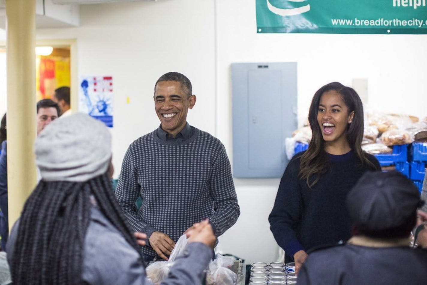 President Barack Obama and his daughter, Malia, hand out food during a Thanksgiving service event at Bread for the City food bank in Washington, Nov. 26, 2014.