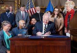 Gov. Tim Walz signs a bill to direct payments to front-line workers and replenish the unemployment trust fund during a ceremony Monday at the State Ca