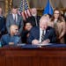 Gov. Tim Walz signs a bill to direct payments to front-line workers and replenish the unemployment trust fund during a ceremony Monday at the State Ca