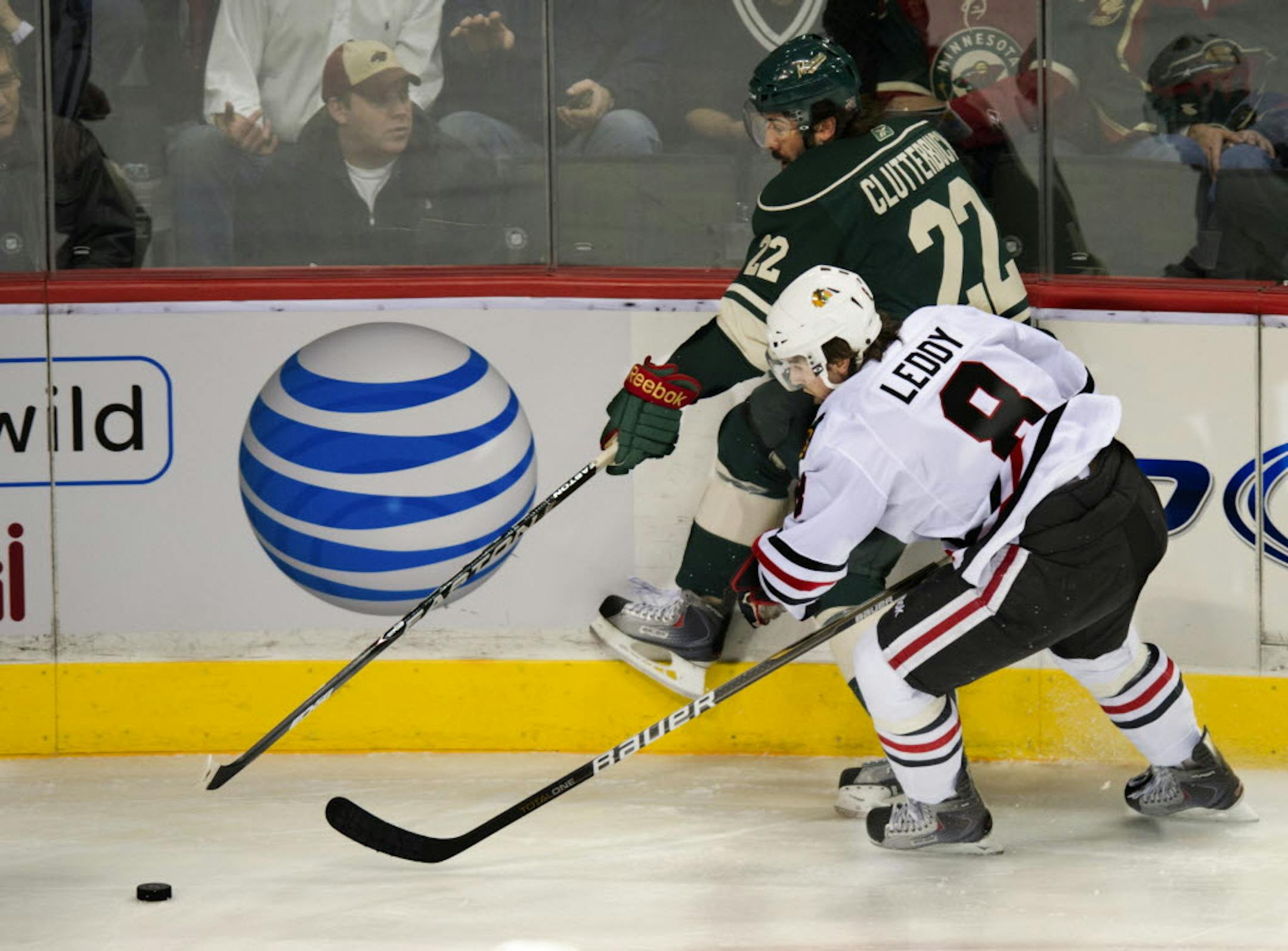 Minnesota's Cal Clutterbuck and Chicago's Nick Leddy scramble for control of the puck.