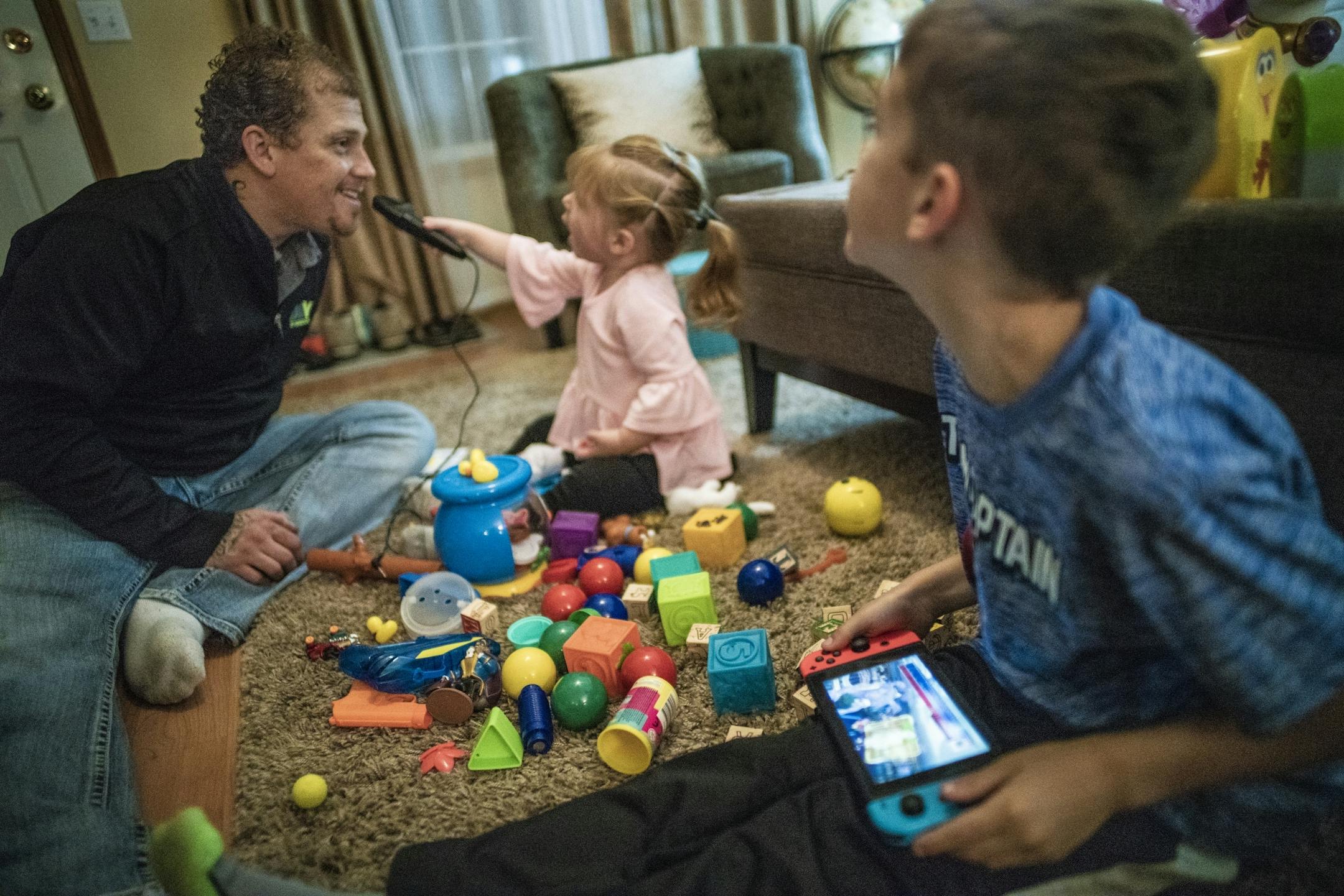 Sabriella,2, tries to get her dad, Alex Kempe to sing karaoke while Asher,7, plays a video game.