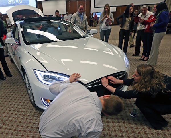 3M employees looked at the Tesla S electric car as part of the 3M celebration of Earth Day with displays of other sustainable 3M products including No