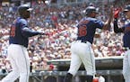 Minnesota Twins' Max Kepler, right, greets Jonathan Schoop and Miguel Sano, left, after they scored on a Byron Buxton single off Texas Rangers pitcher