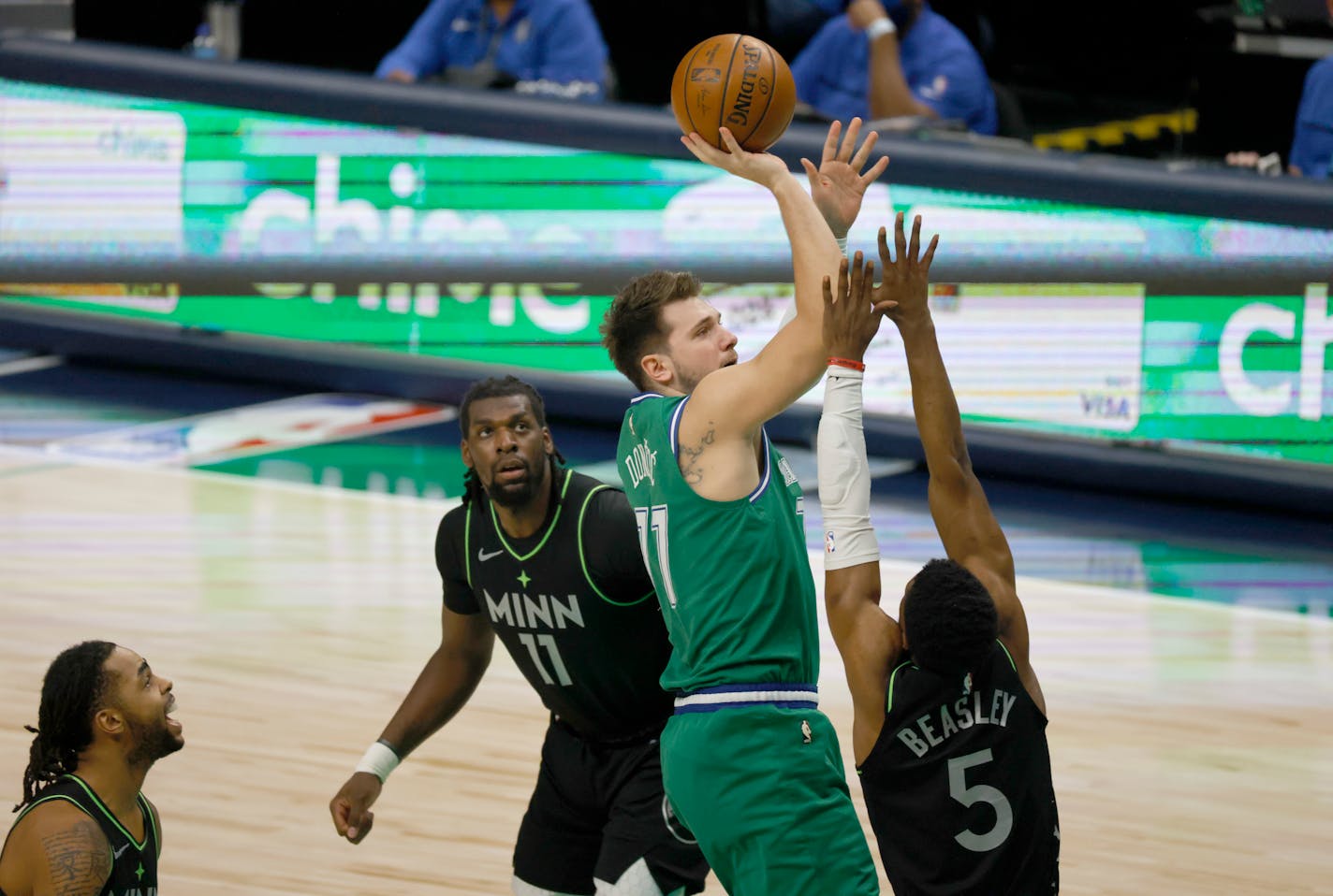 Dallas Mavericks guard Luka Doncic (77) shoots over Minnesota Timberwolves center Naz Reid (11) and Minnesota Timberwolves guard Malik Beasley (5) during the first half of an NBA basketball game, Monday, Feb. 8, 2021, in Dallas. (AP Photo/Ron Jenkins)