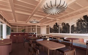 A long room with wood tables, a bar at the back and walls with prints of black and white trees.