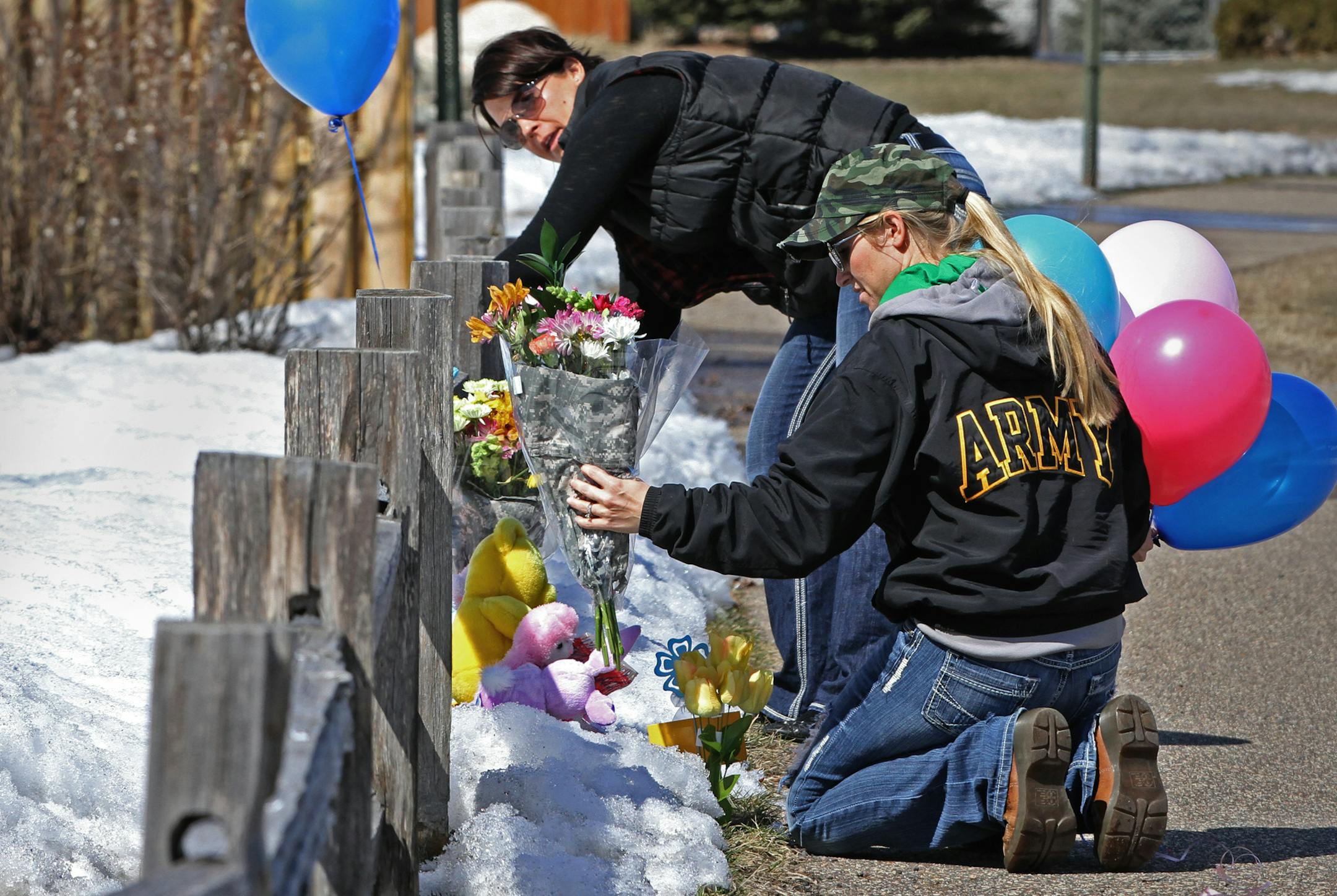 Jodie Weg­leitner, left, and Amanda Stenberg placed flowers at the Shields home in Zimmerman. The husbands of the two women serve in the National Guard with Mark Shields, husband of Stephanie Shields. Bruce Bisping